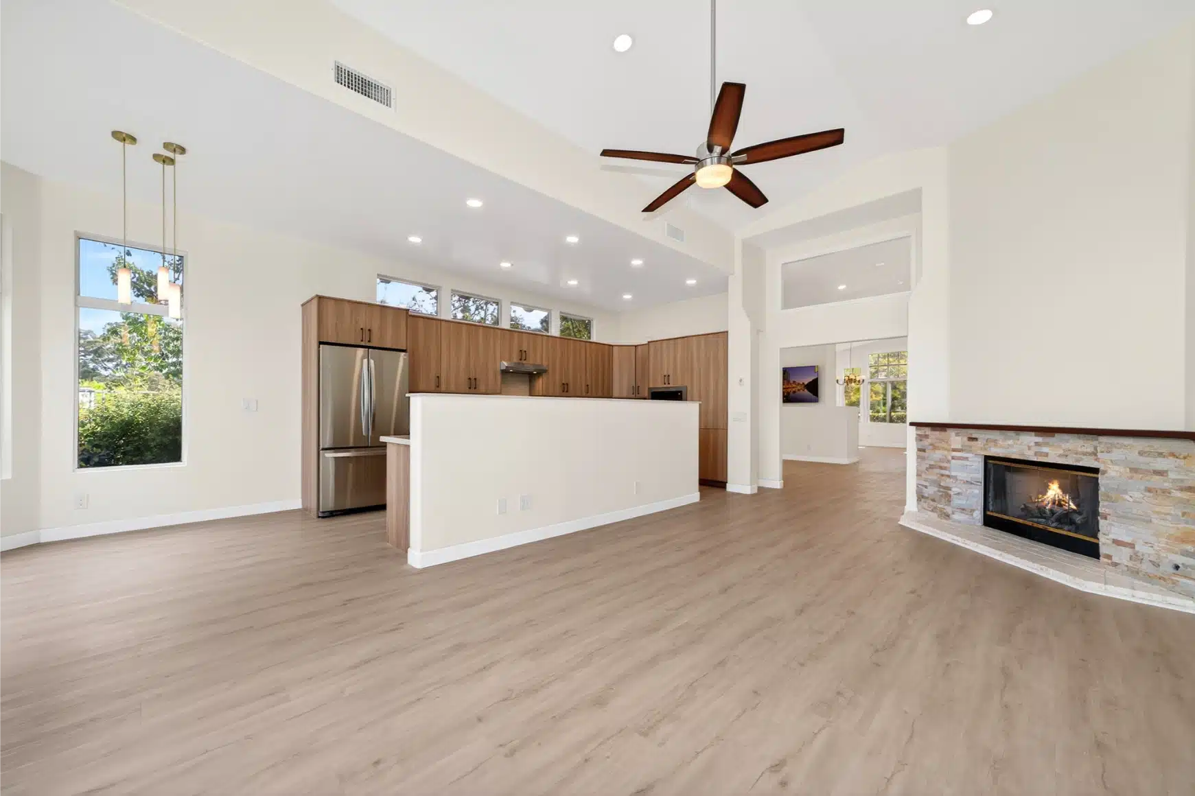 Whole-house remodel in San Diego with vaulted ceilings, a stone fireplace and an open kitchen beyond