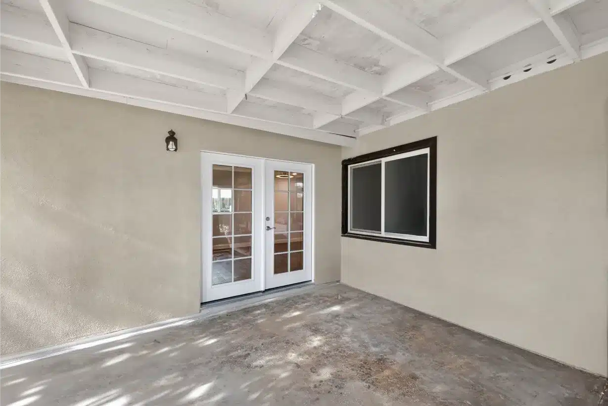 Covered outdoor room with an exposed beamed ceiling and French doors