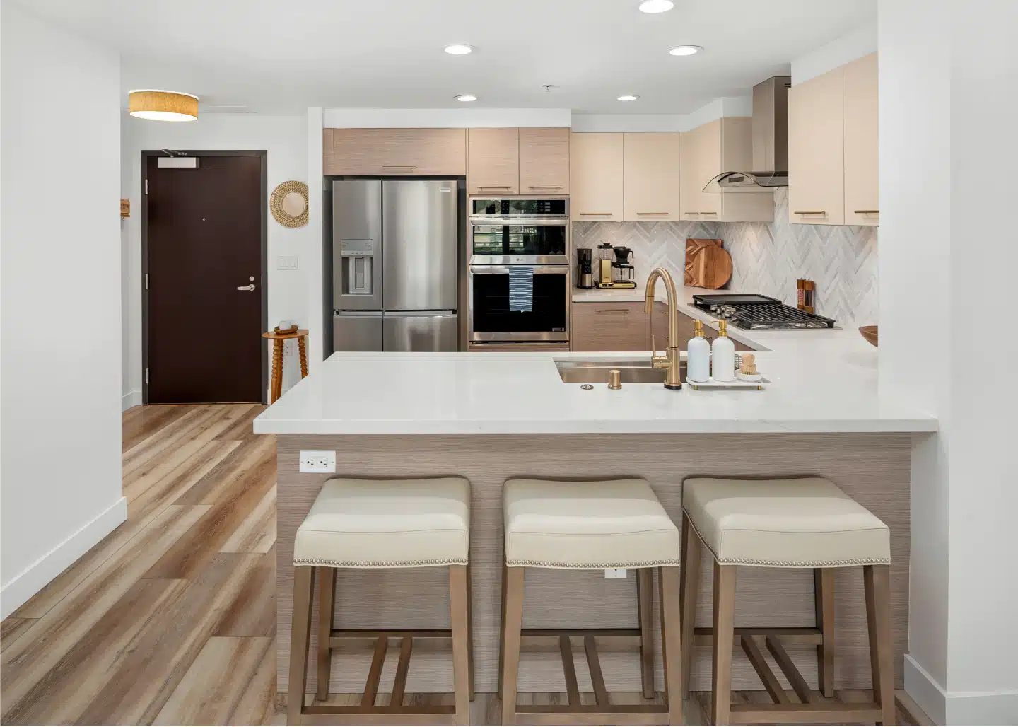Kitchen peninsula with three upholstered stools in the remodelled Little Italy condo