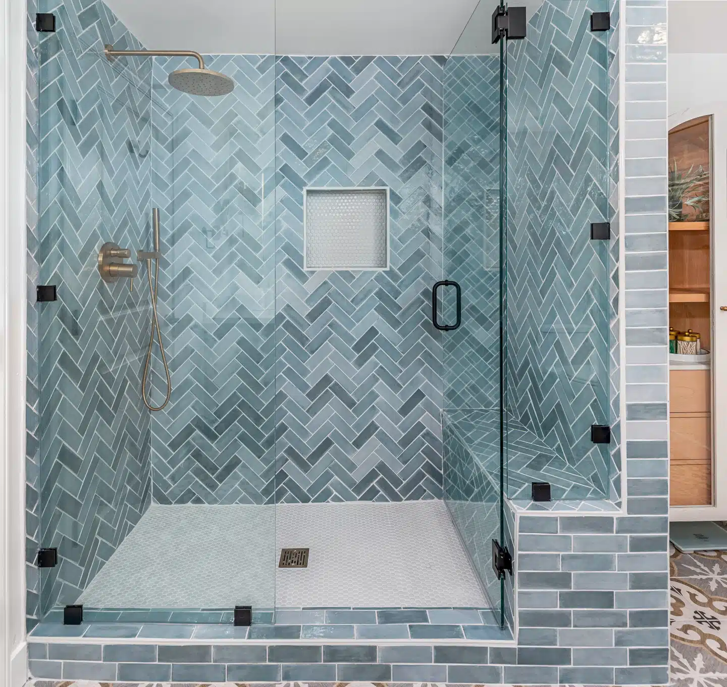 Shower detail showing the blue-green herringbone tile and recessed niche