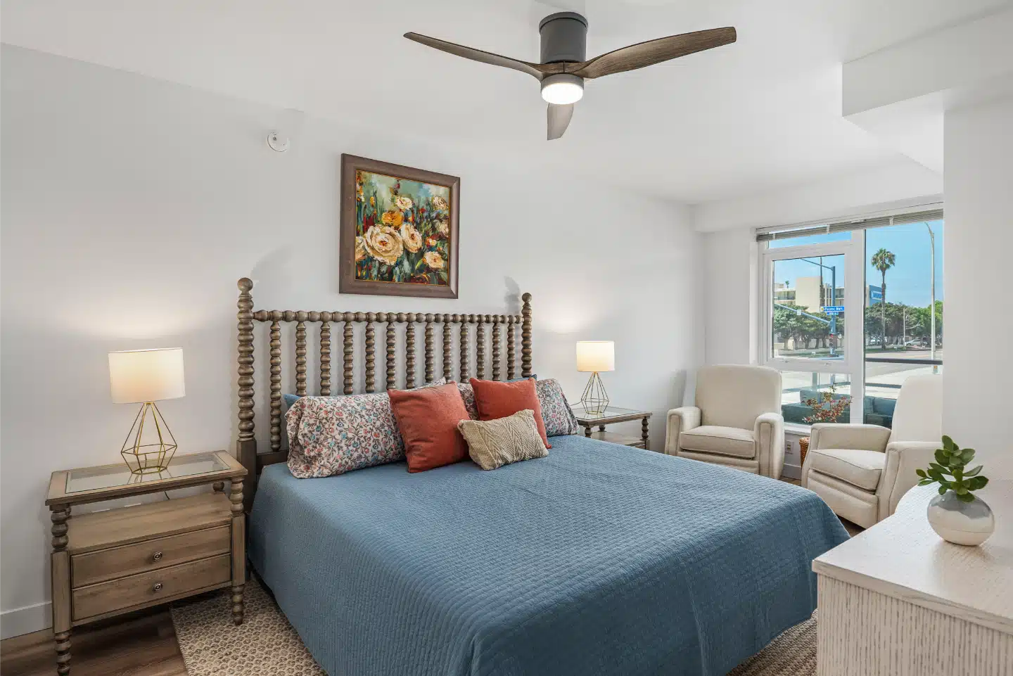 Bedroom with a ceiling fan and window to the balcony in the remodelled condo