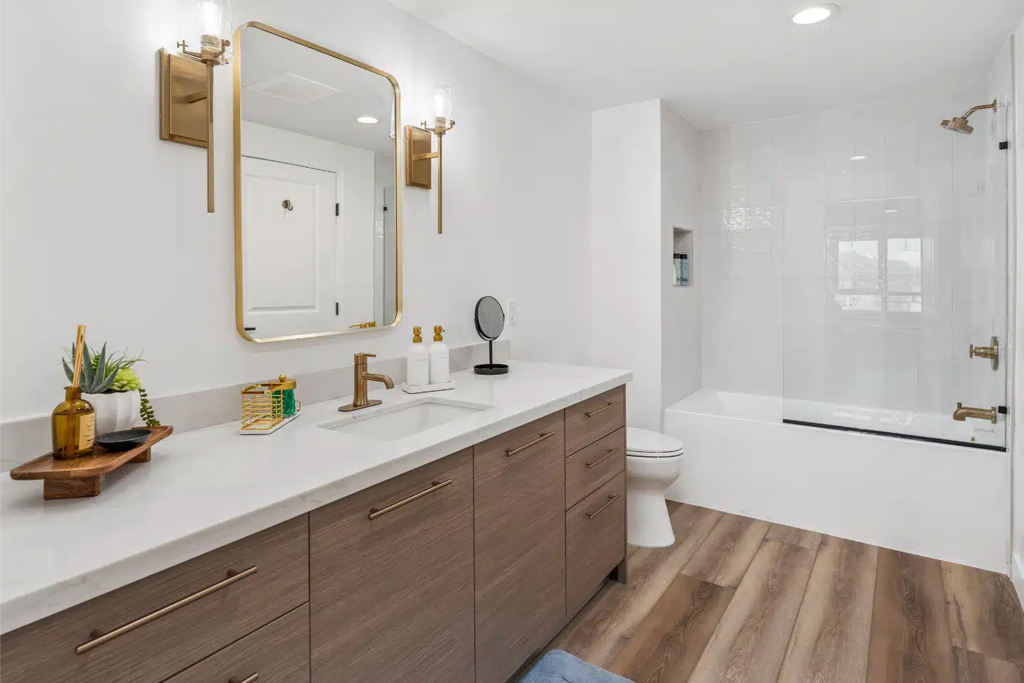Bathroom vanity and tub-shower finished with brass fixtures