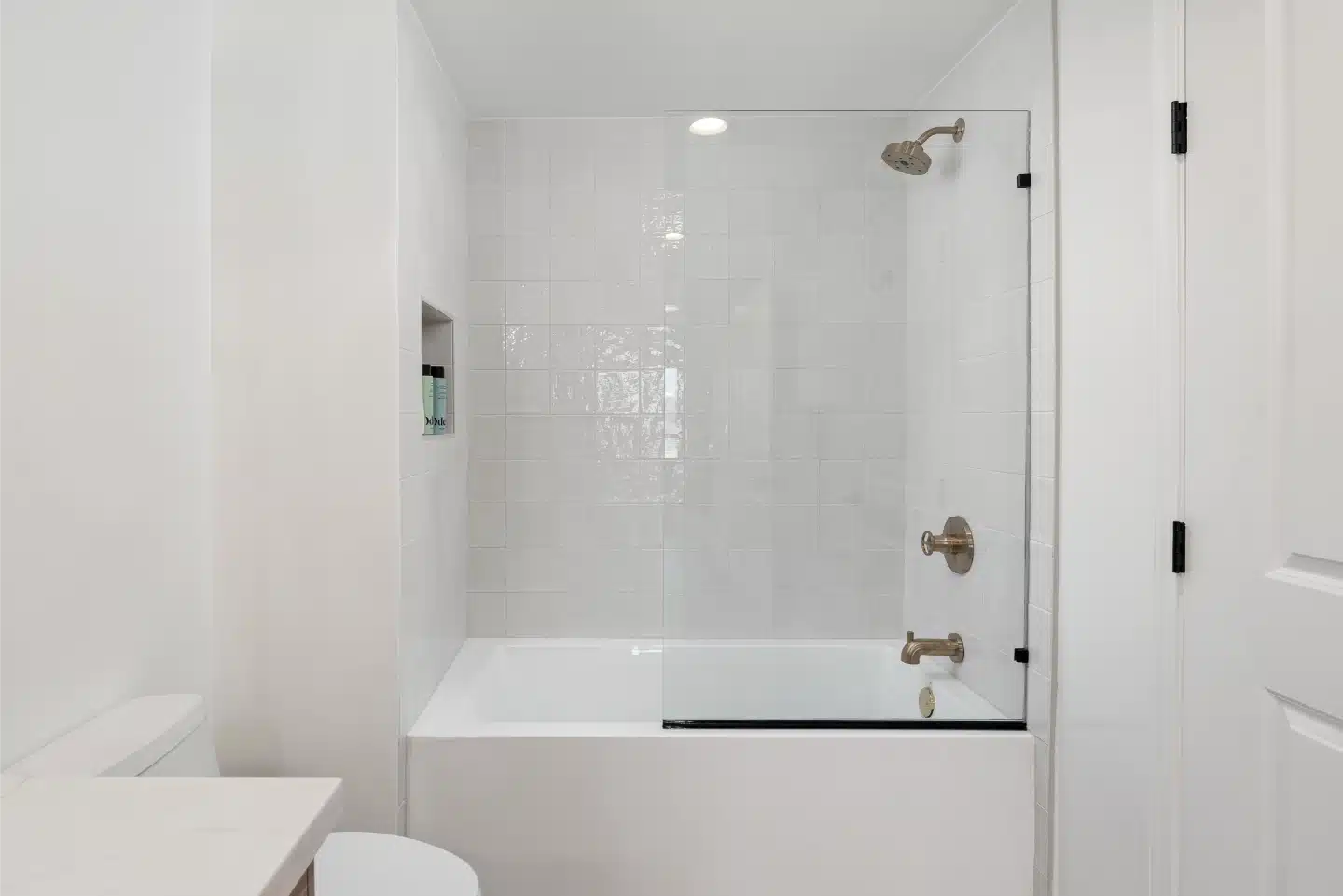 White tub-shower with brass fixtures in the second bathroom