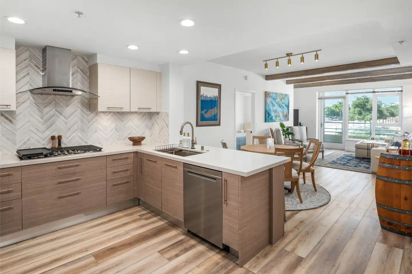 Remodelled Little Italy condo kitchen opening onto the dining and living area, with light oak plank flooring