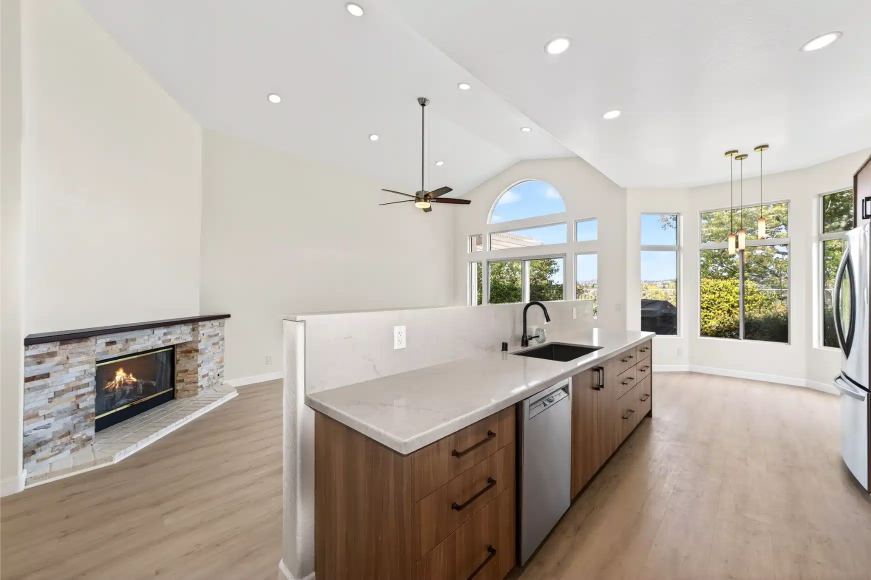 Kitchen island and rebuilt stone hearth seen together under the vaulted ceiling