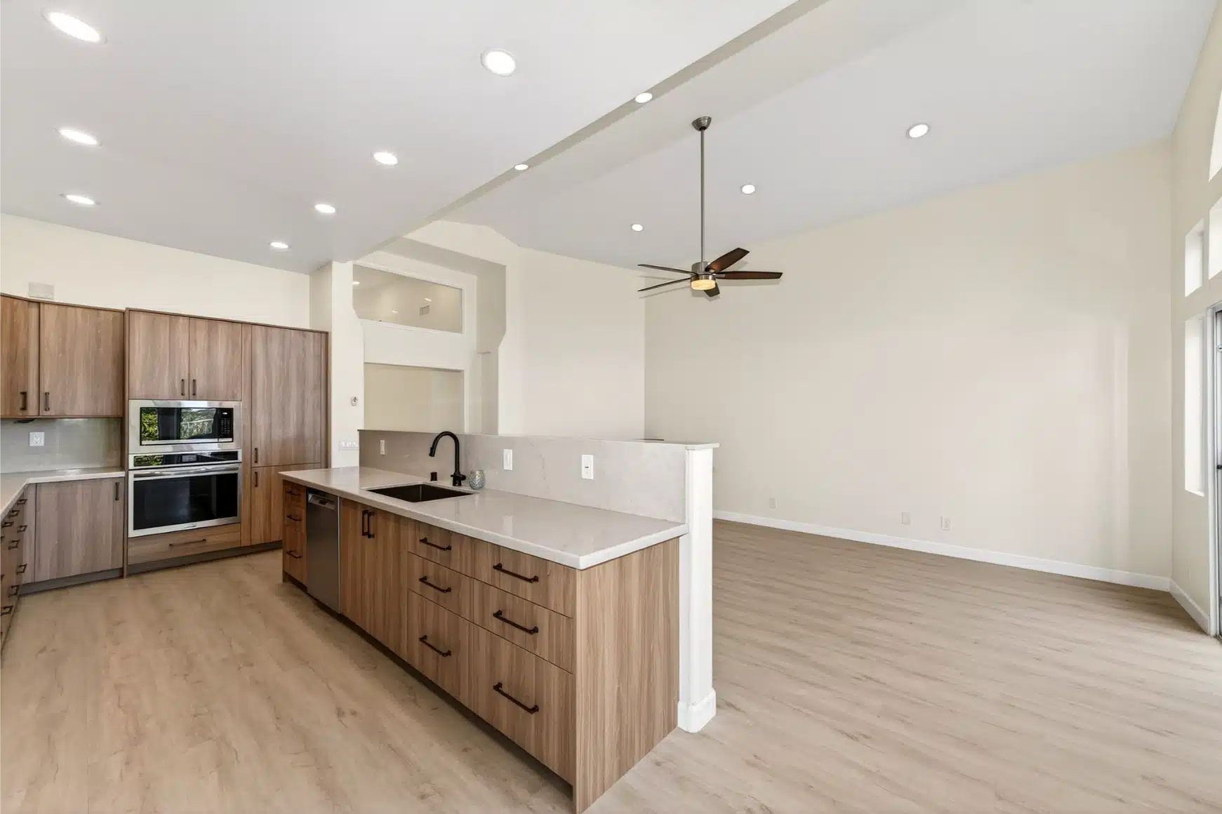 Kitchen island with wall ovens and the open living space beyond