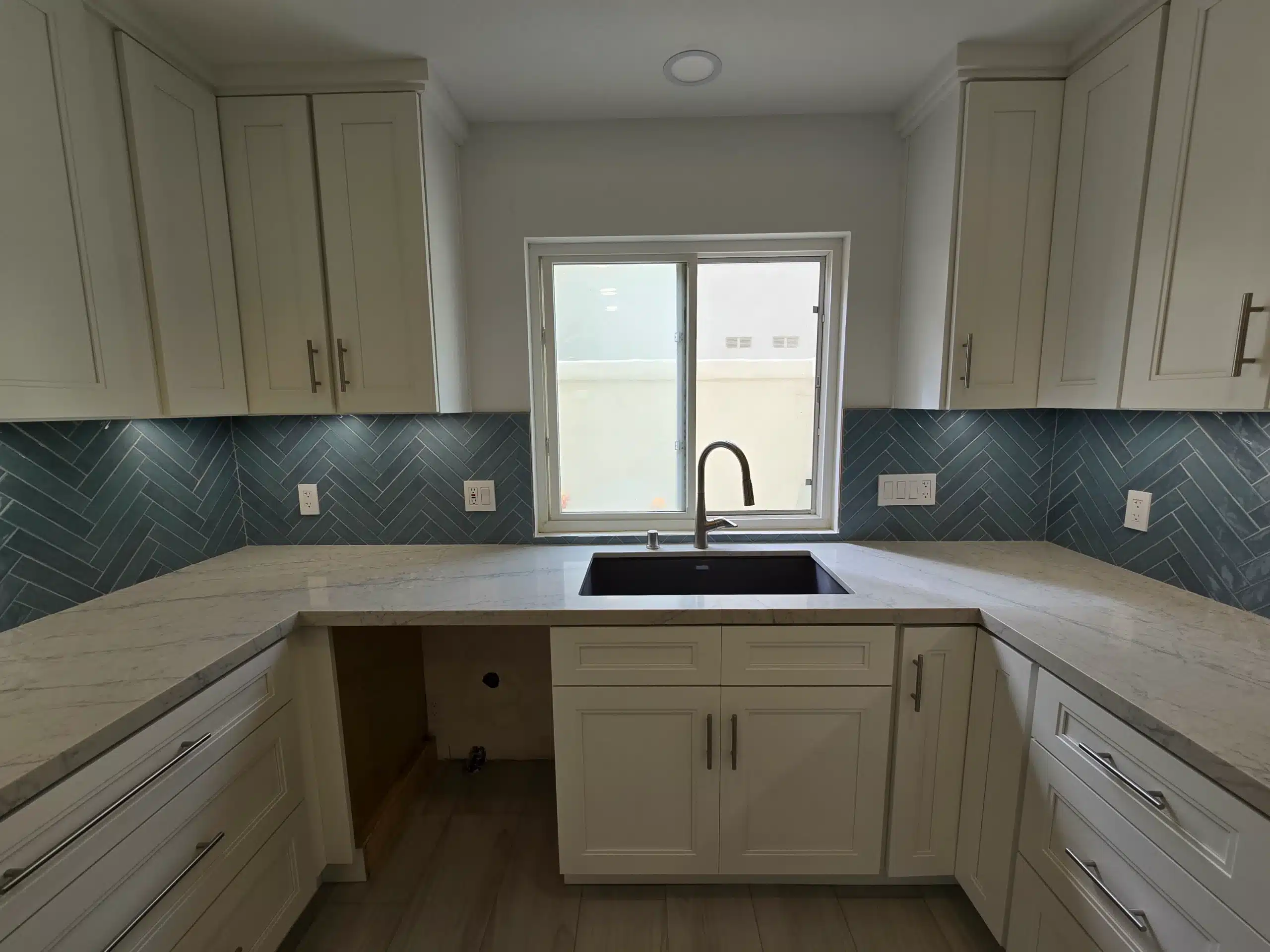 Encinitas kitchen peninsula with a waterfall quartz return and herringbone tile behind