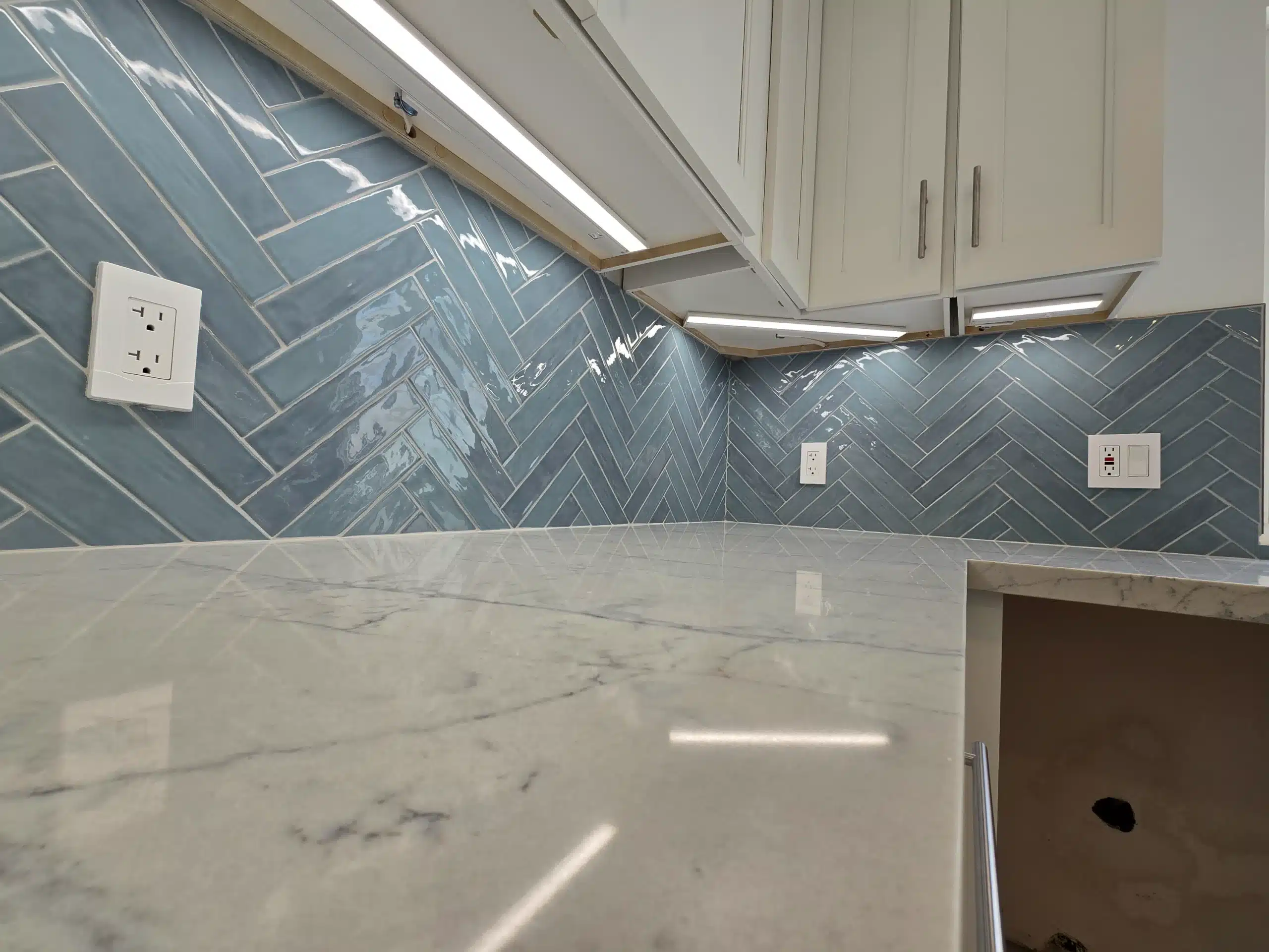 Close view of the blue-green herringbone tile backsplash and quartz counter in the Encinitas kitchen