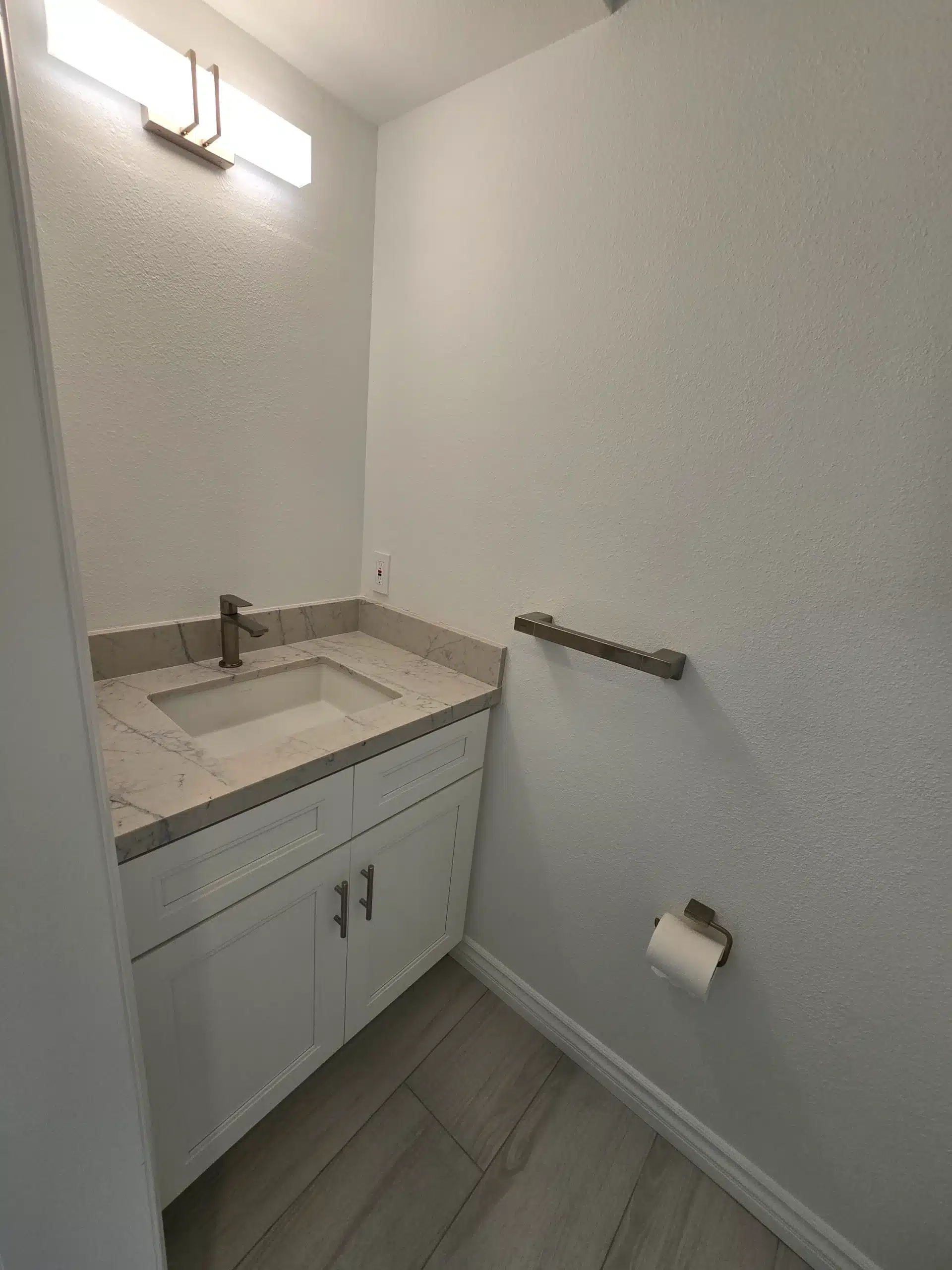 Second bathroom with a single vanity, marble-look counter and linear light fixture