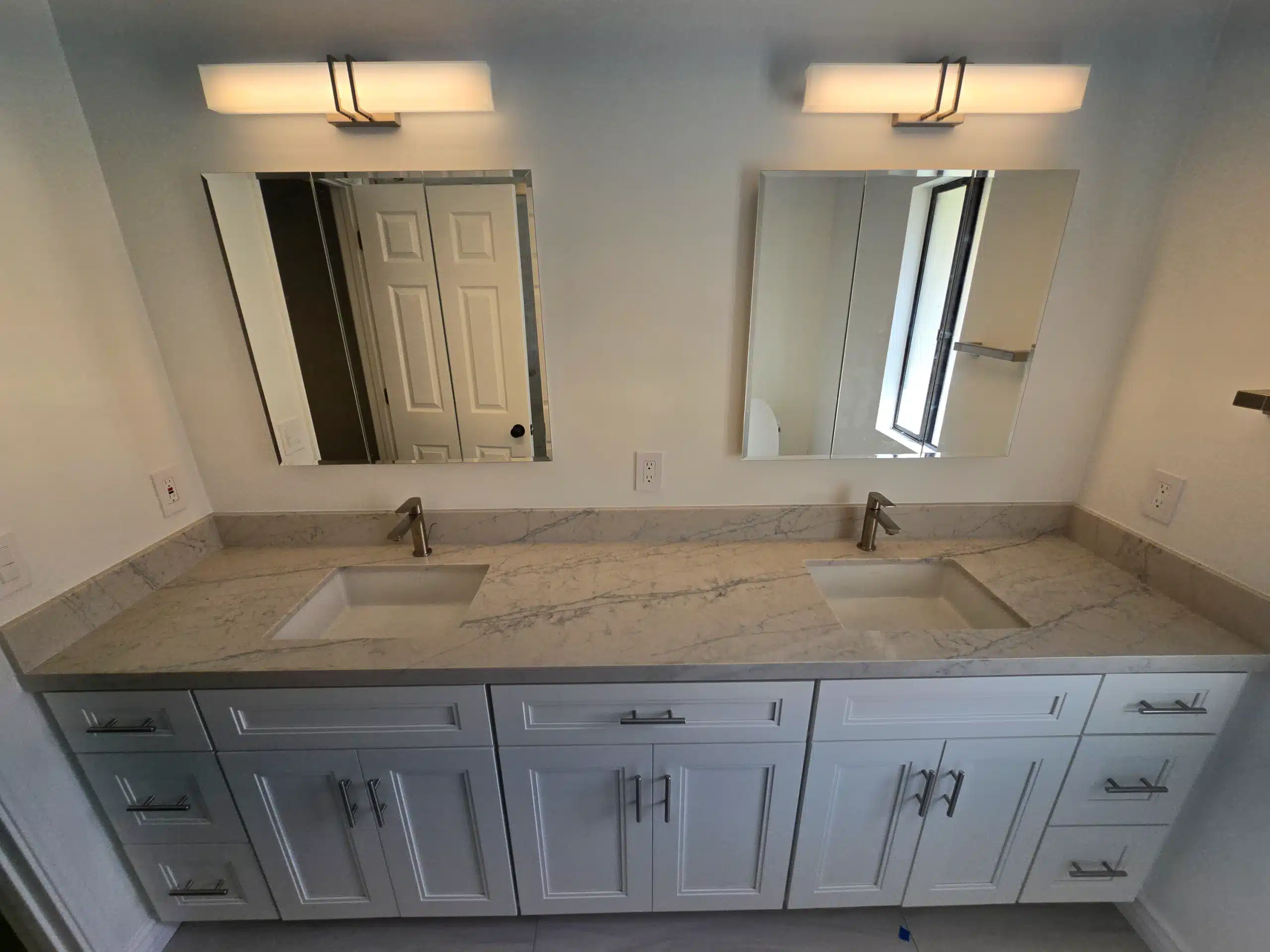 Double vanity basins and framed mirrors reflected in the Encinitas bathroom