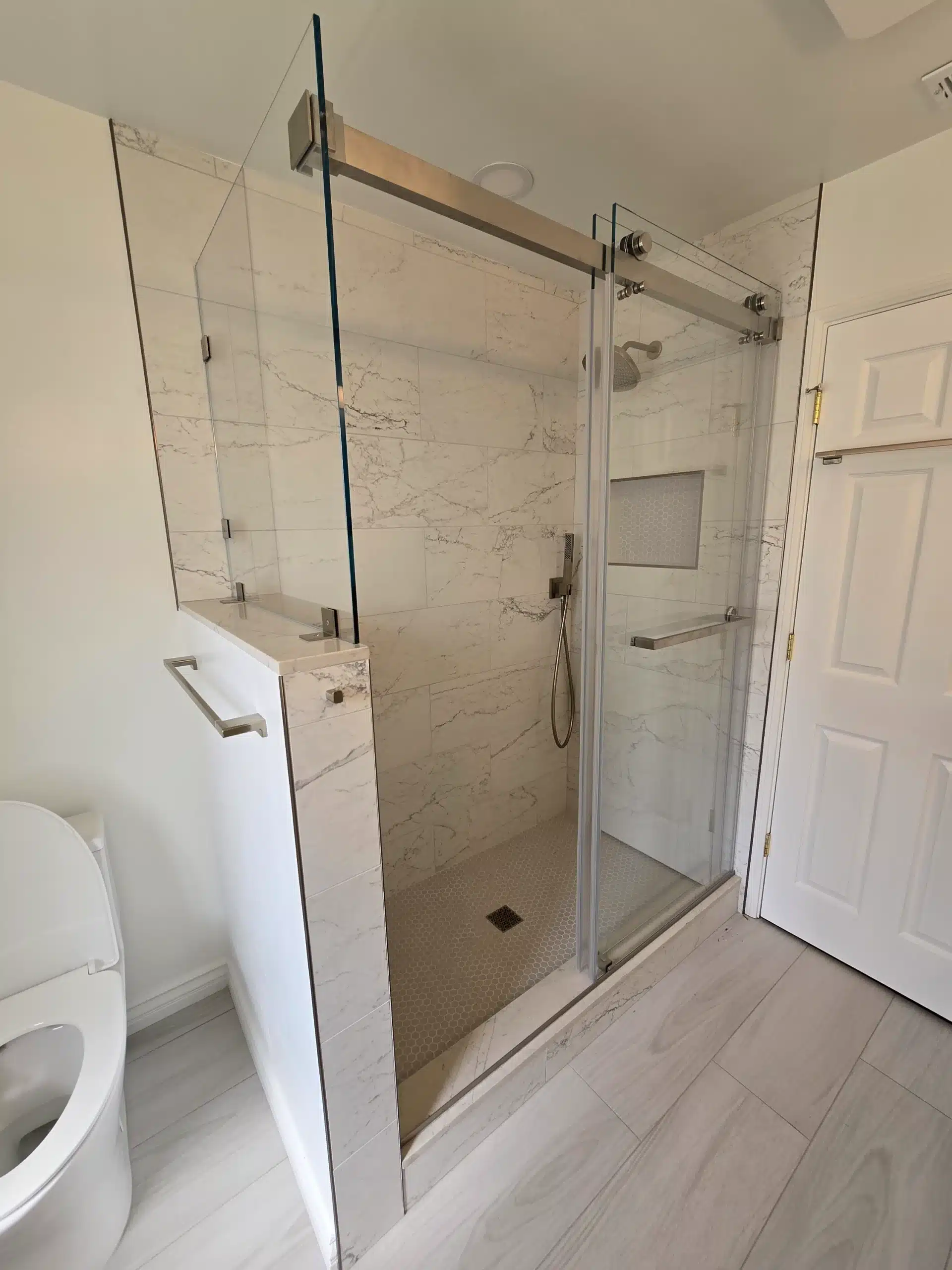 Walk-in shower with sliding frameless glass and large-format marble-look wall tile