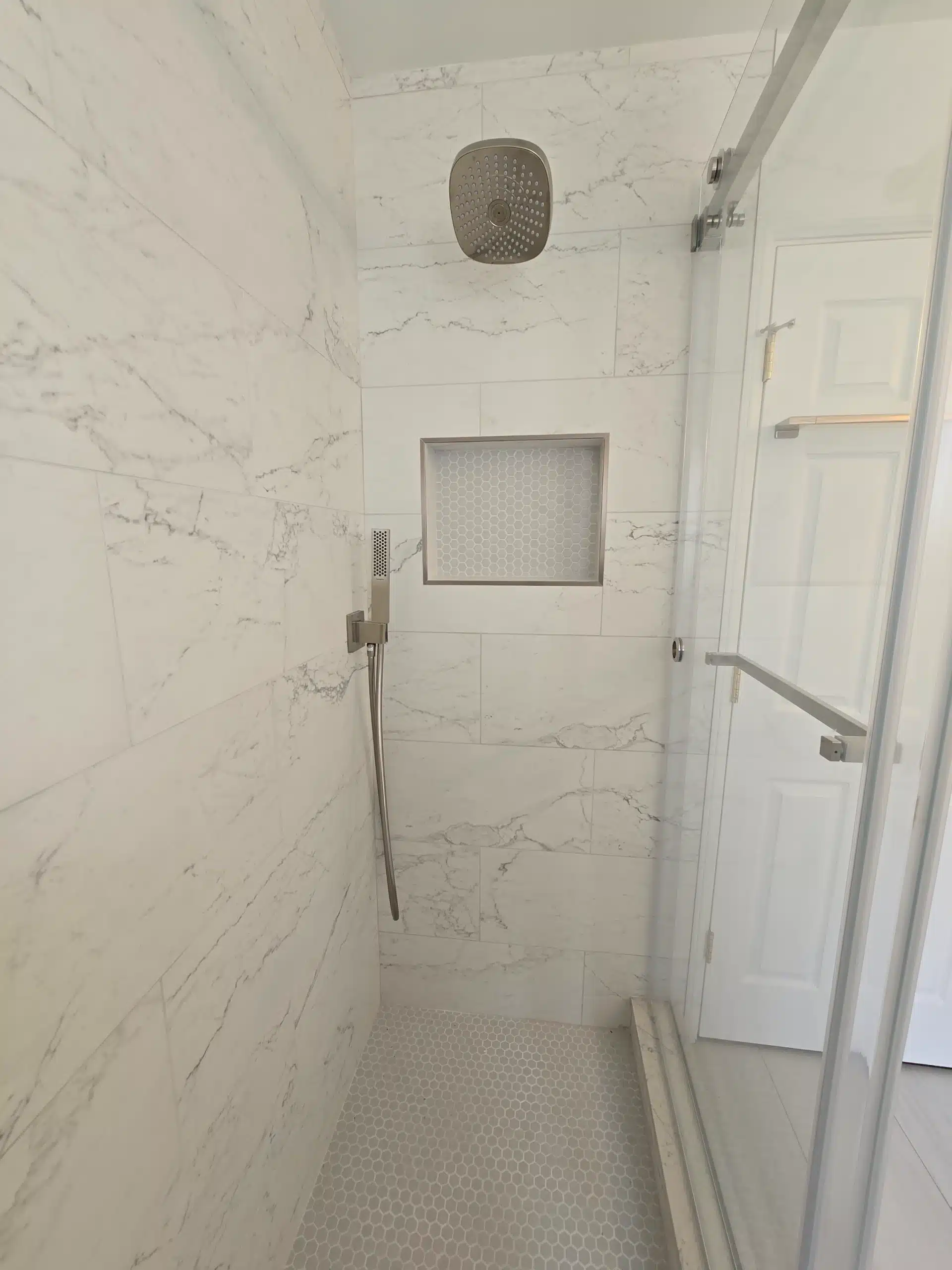 Recessed shower niche in marble-look porcelain with a handheld shower set