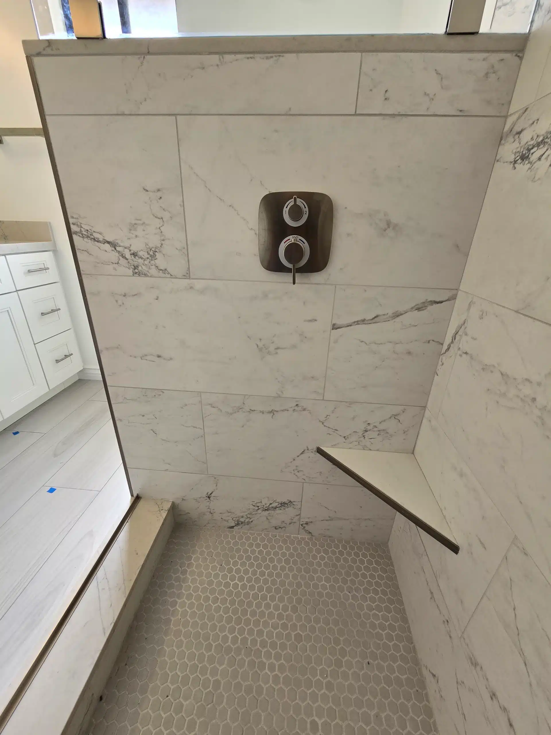Shower bench and recessed control set into marble-look porcelain wall tile