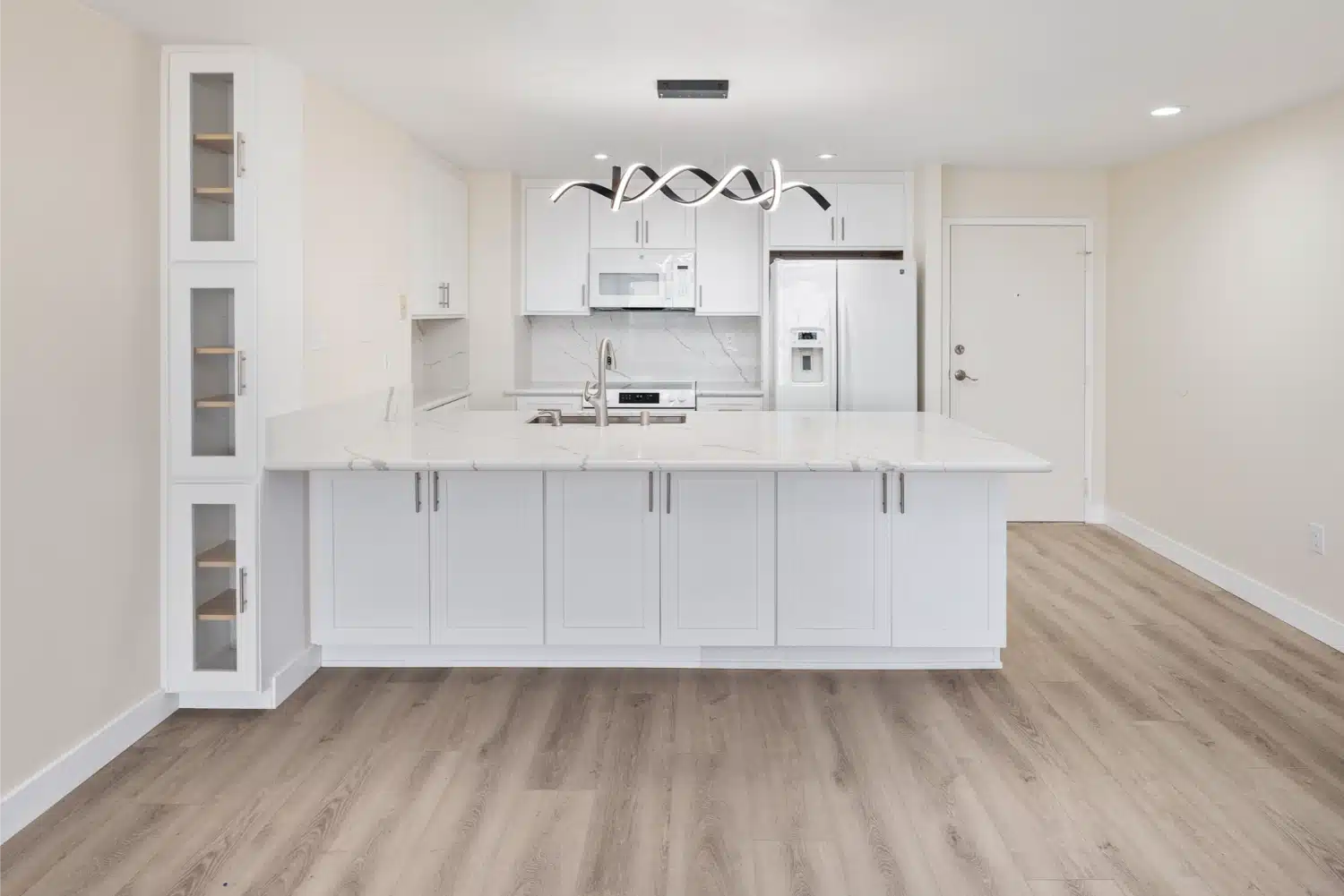 Remodelled condo kitchen with white shaker cabinetry, a marble-look island and a pendant cluster above