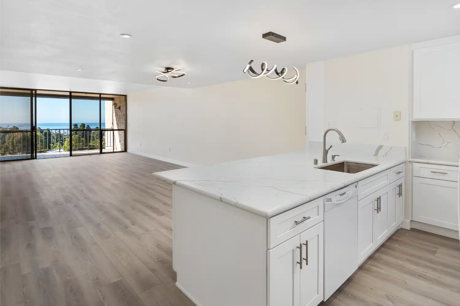 Remodelled kitchen and living area in a La Jolla high-rise condo, opening onto a balcony with an ocean view