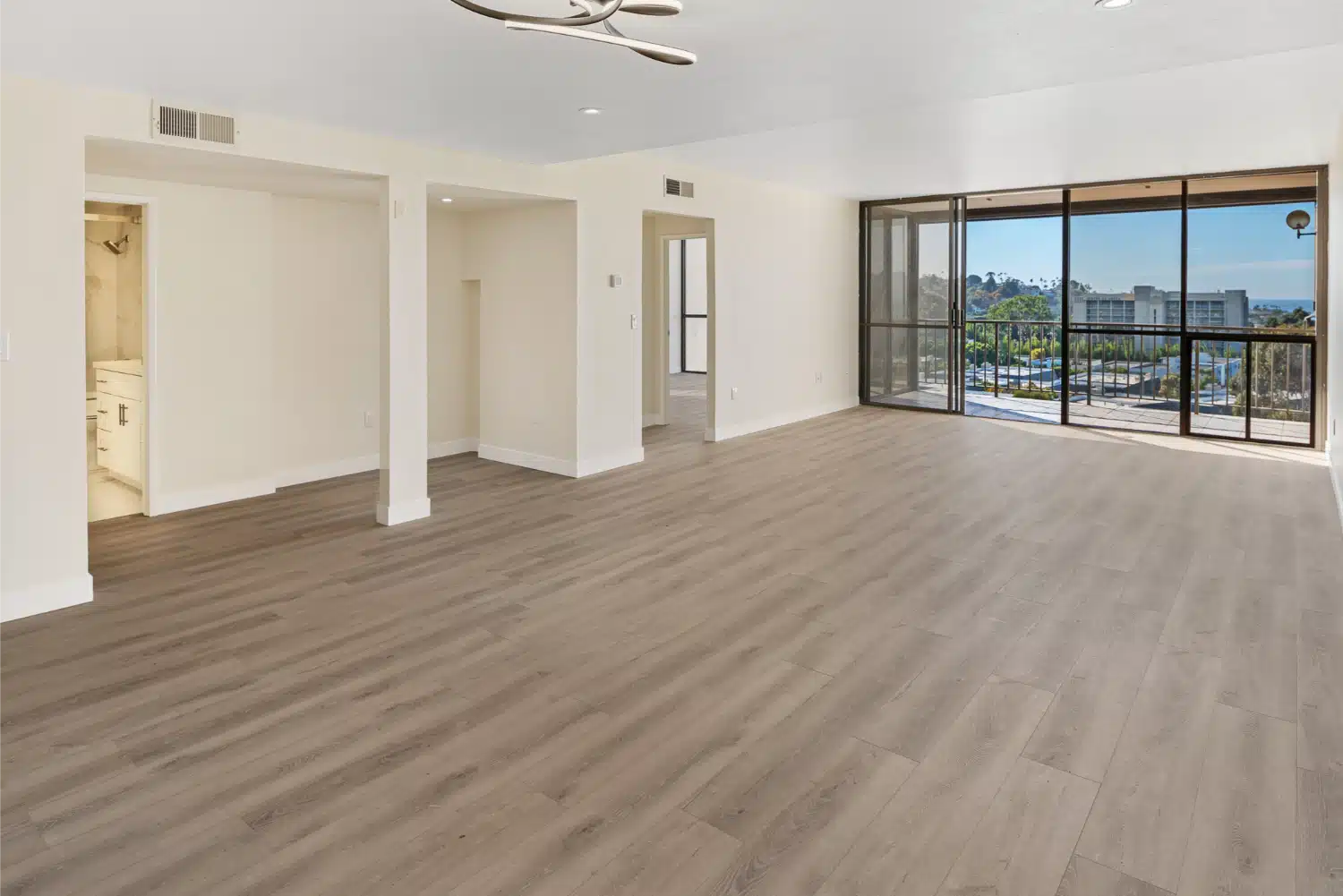 Open living space with new plank flooring running through to the balcony