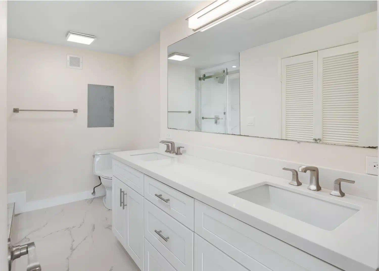 Bathroom with a double vanity, wide mirror and tub in the remodelled La Jolla condo
