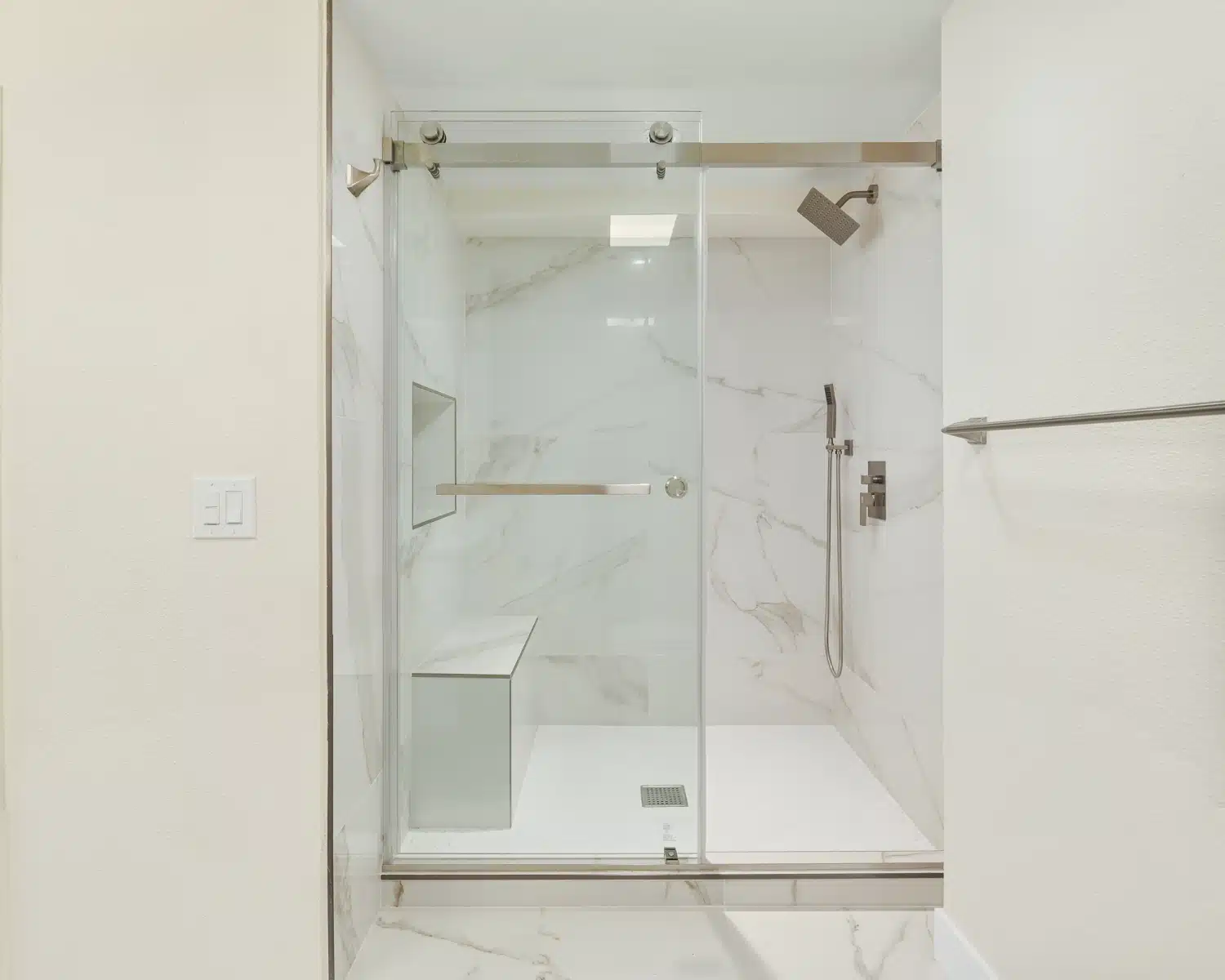 Walk-in shower with frameless glass and a built-in bench