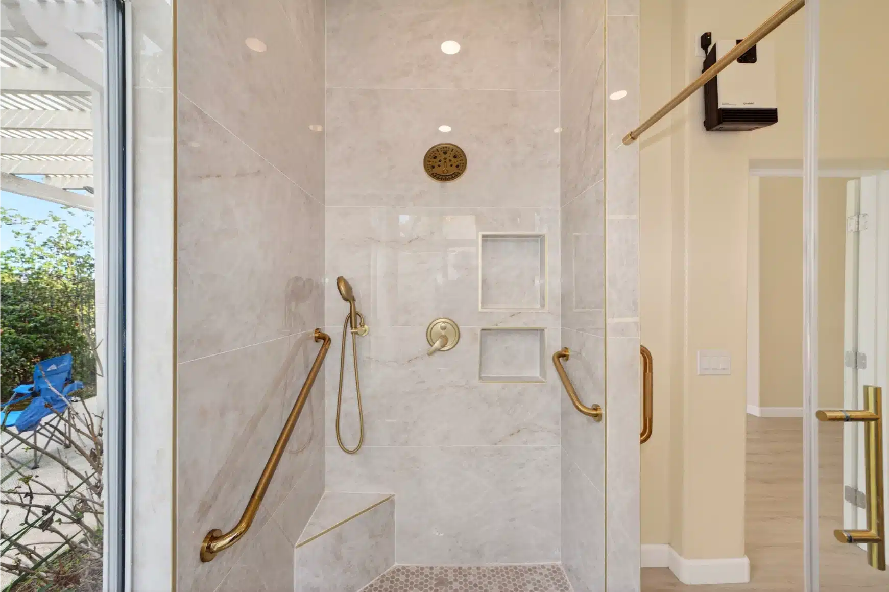Walk-in shower with grab bars, a flush entry and brass fixtures