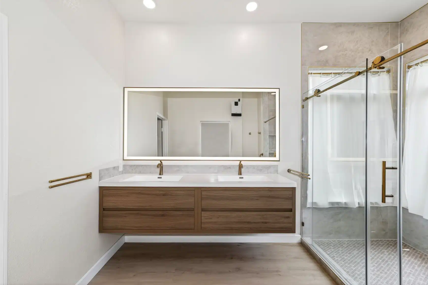 Primary bathroom with a floating oak double vanity and a backlit mirror