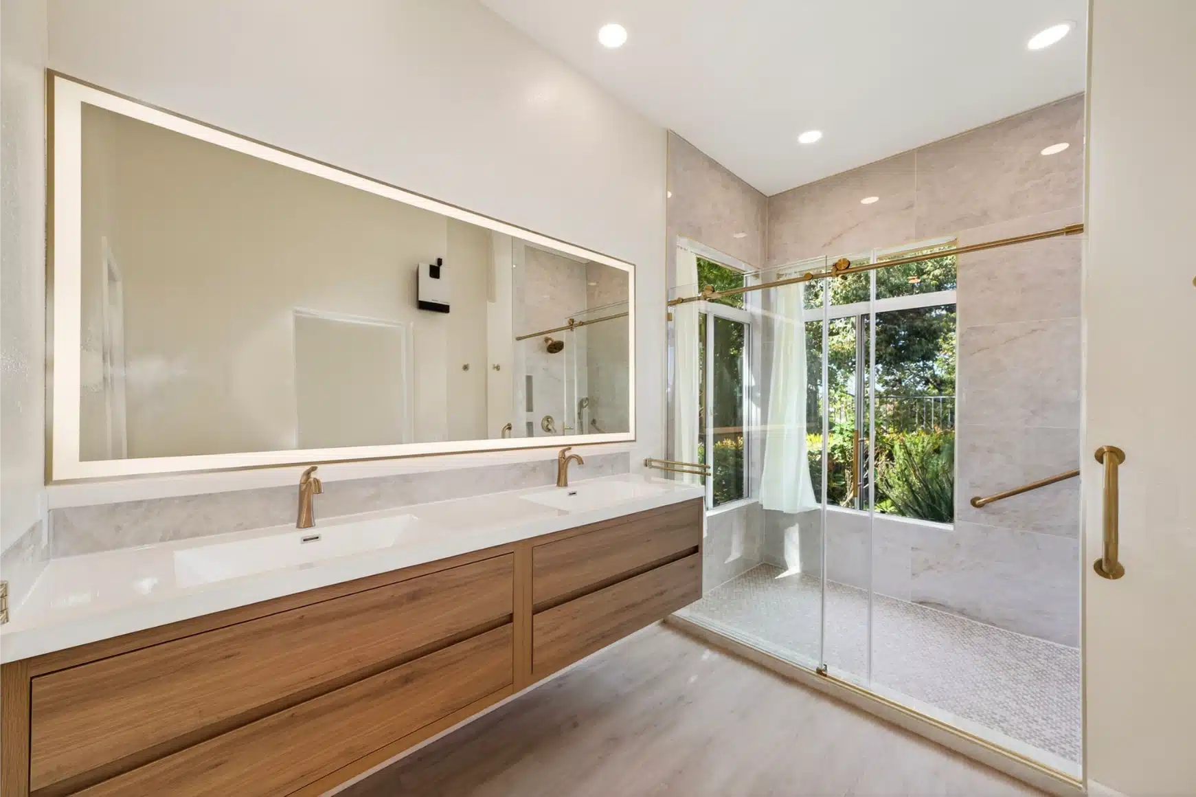 Backlit mirror above the oak vanity, with the shower beyond