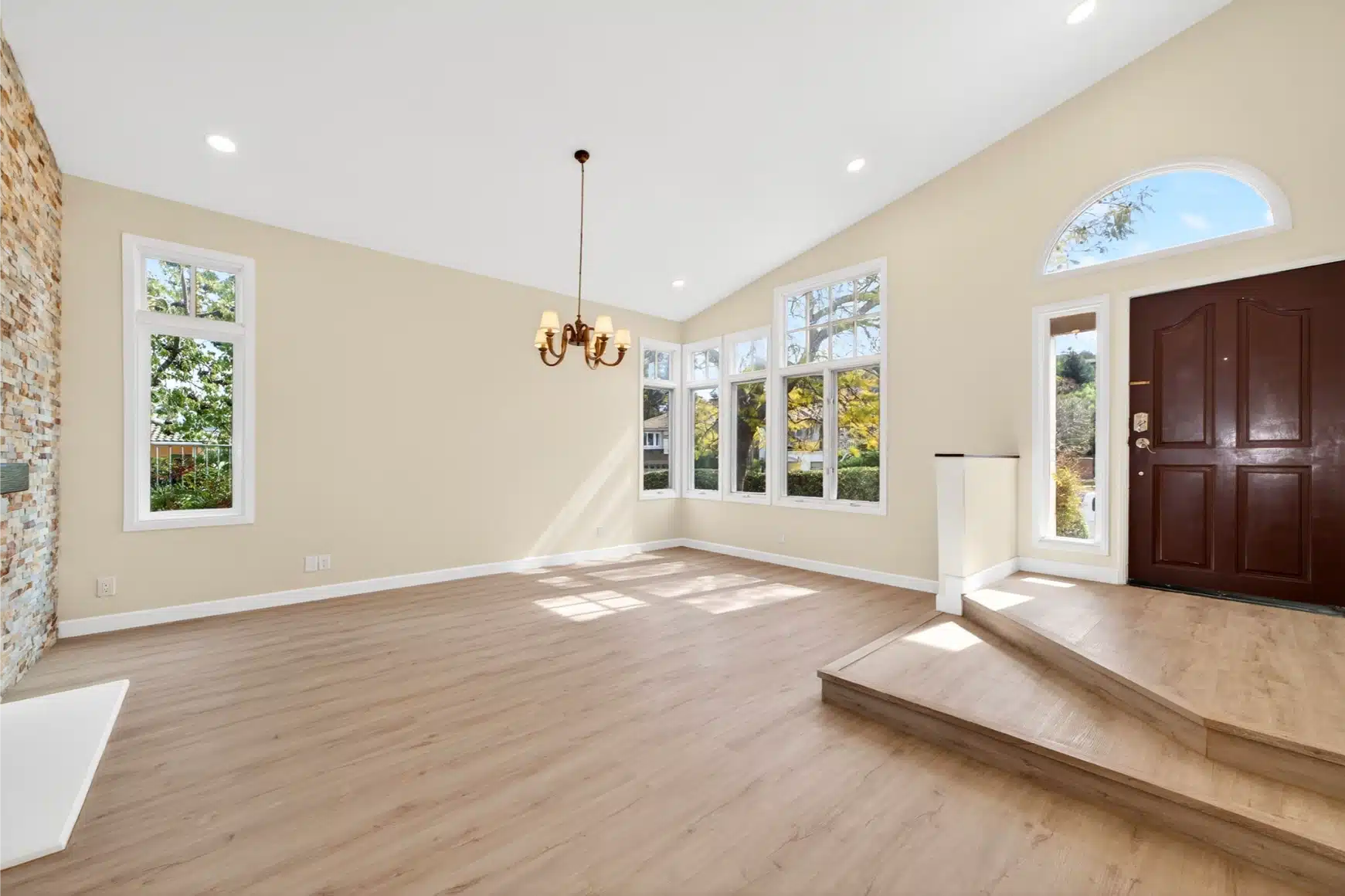 Entry and living area under the vaulted ceiling, with the stone fireplace and arched windows