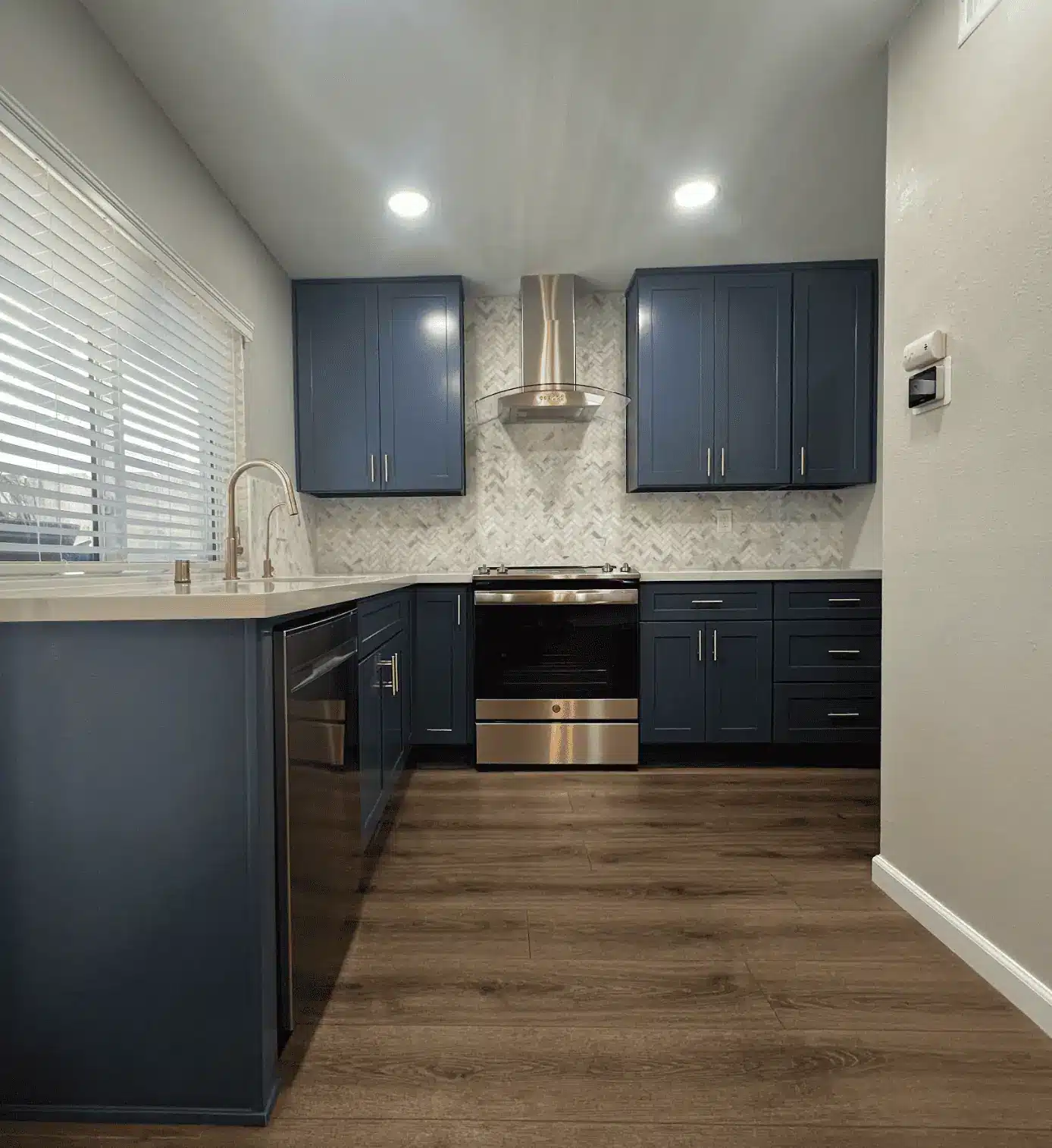 Kitchen remodel with navy cabinetry, white tile backsplash and a stainless steel range