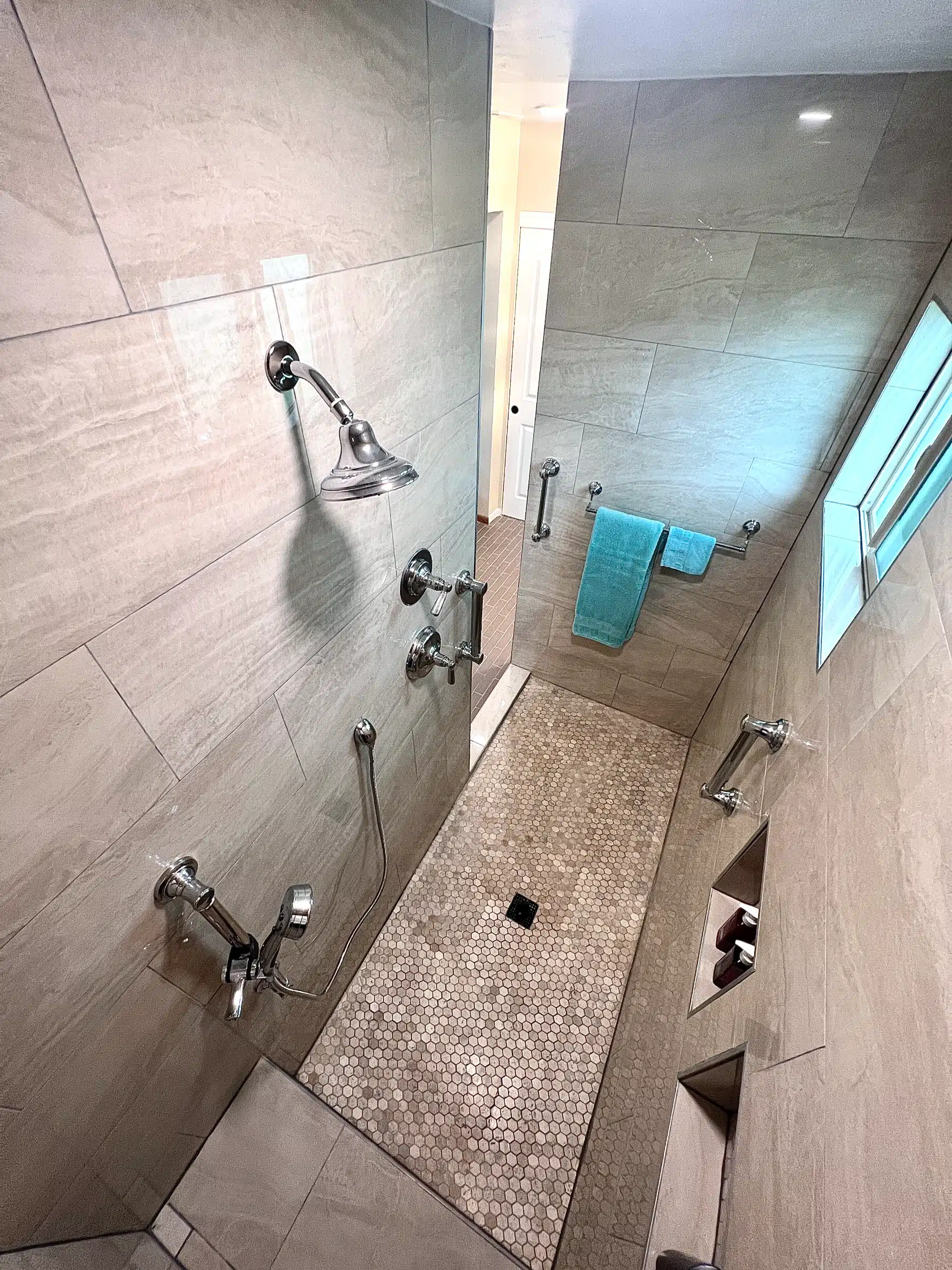 The accessible shower during tiling, with the grab bars and bench already set