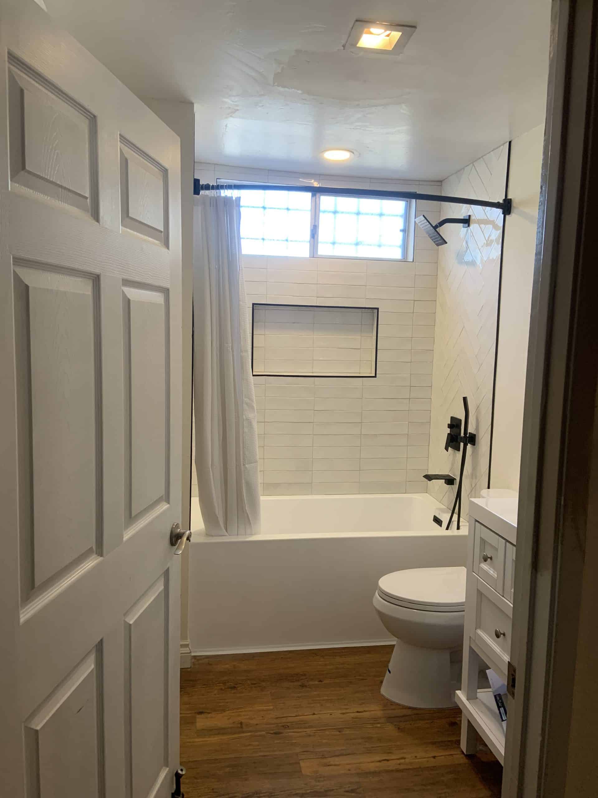 Completed bathroom remodel in La Mesa with a tiled tub surround and matte black fixtures