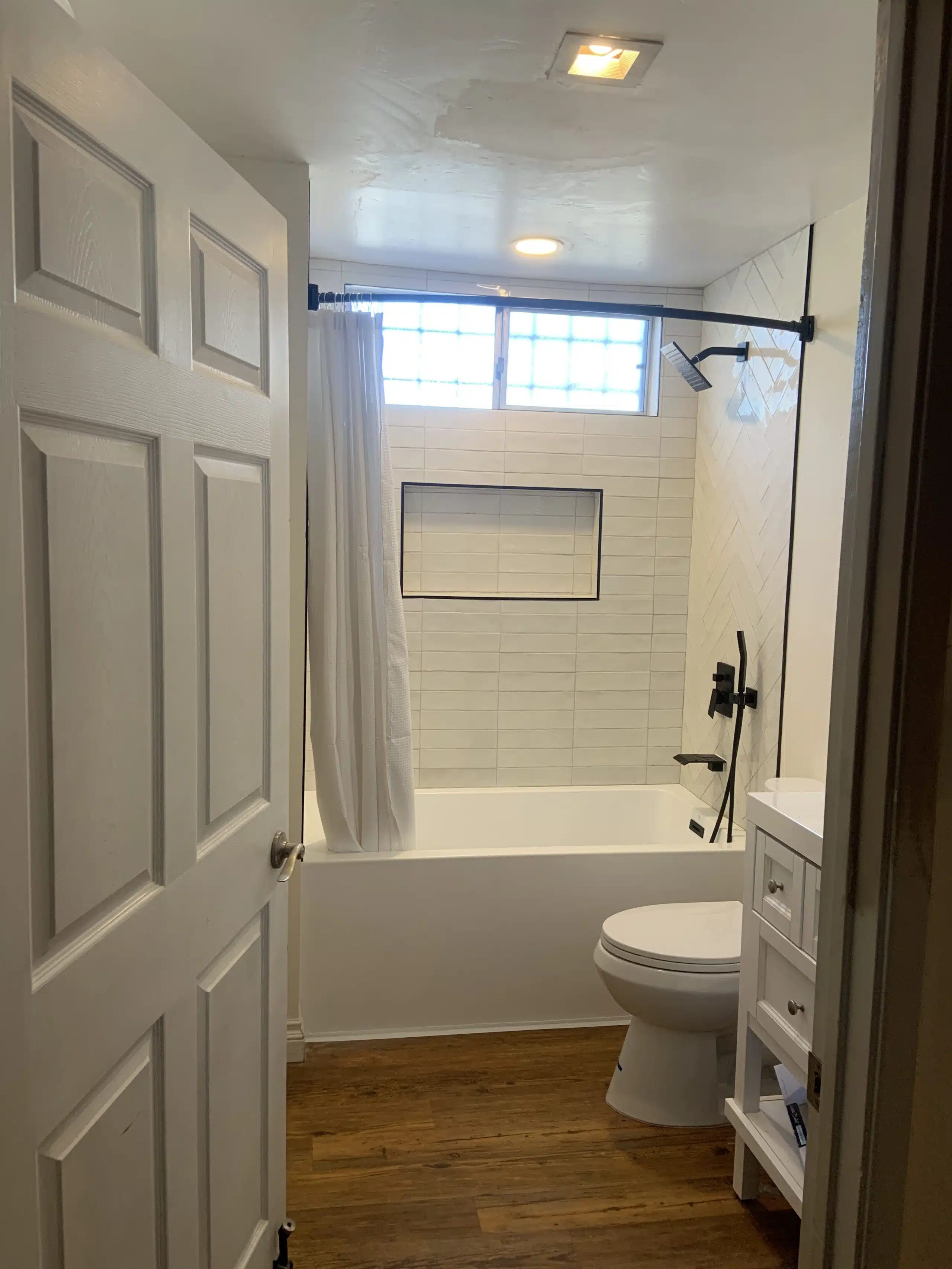 Completed bathroom remodel in La Mesa with a tiled tub surround and matte black fixtures