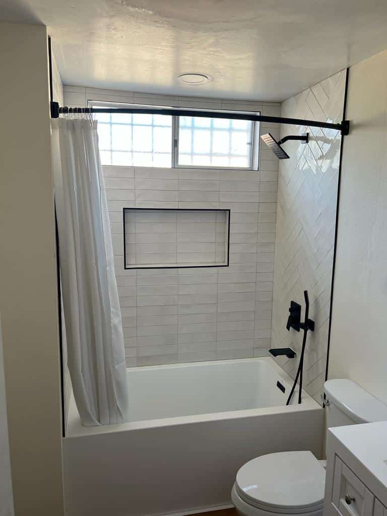 The same La Mesa bathroom after the remodel, with a tiled surround, recessed niche and matte black fixtures