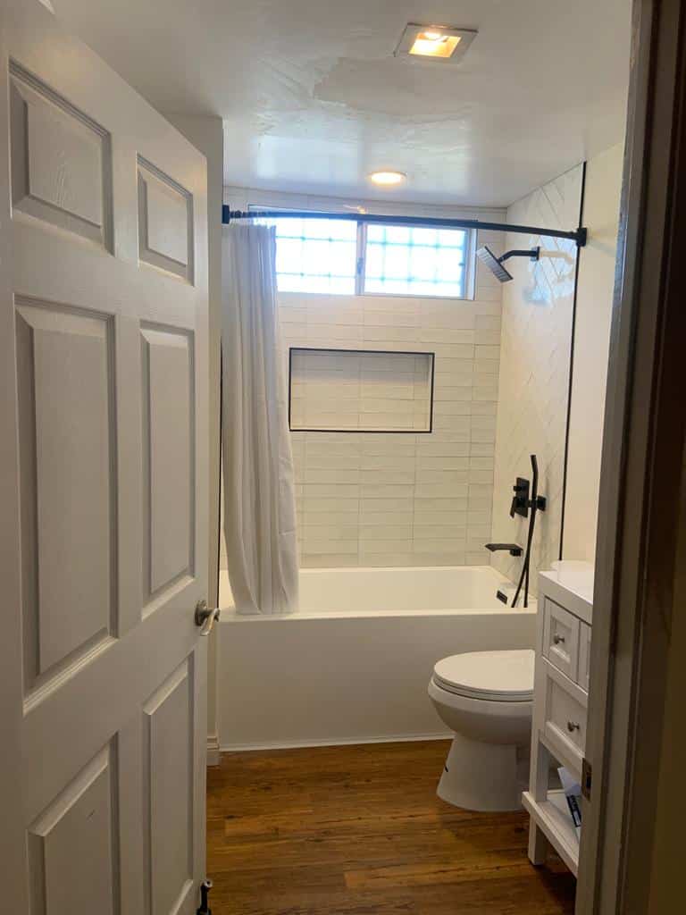 Tiled tub surround with the recessed niche and matte black tub filler