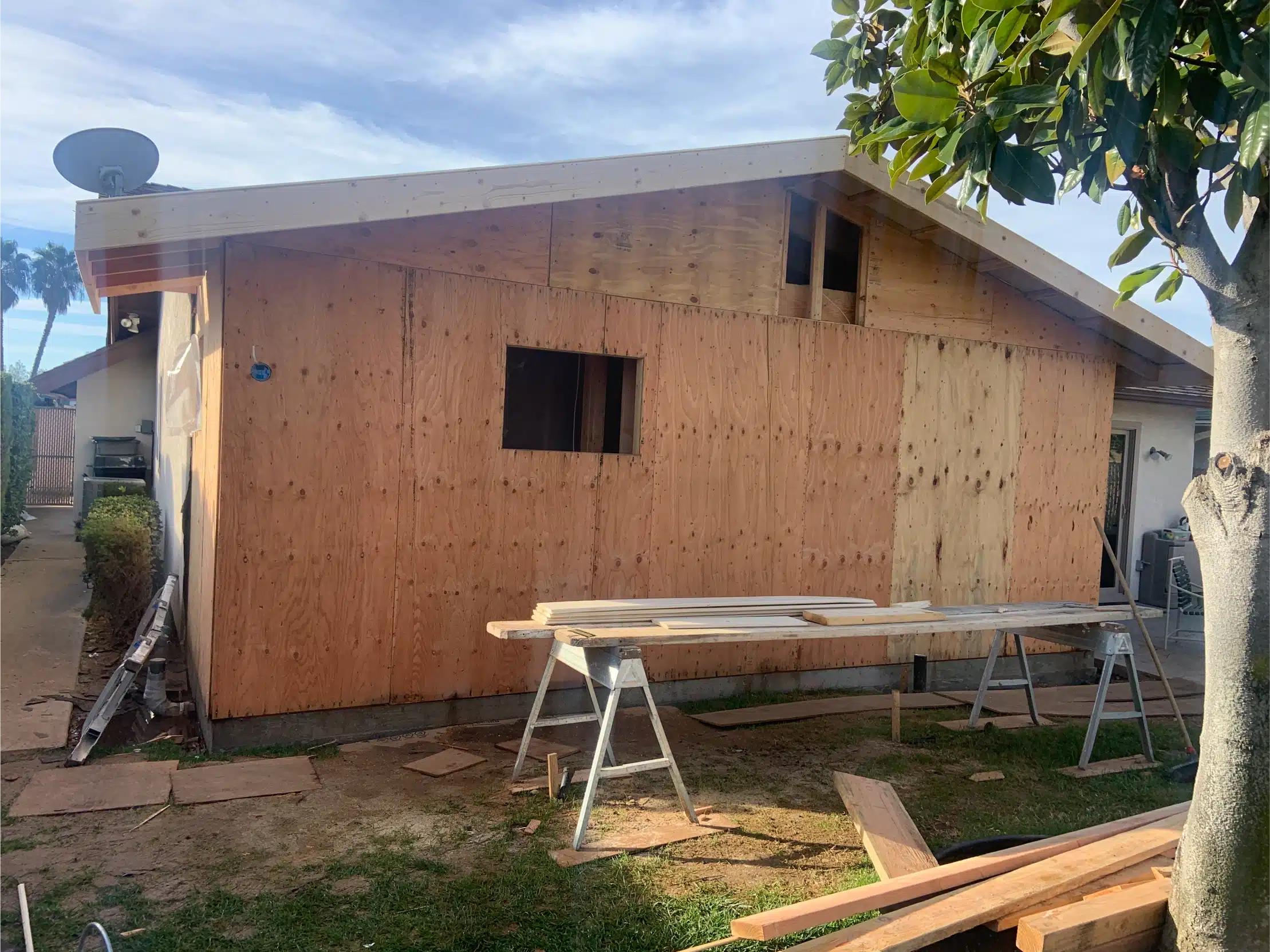 The addition sheathed in plywood with the roof framed above