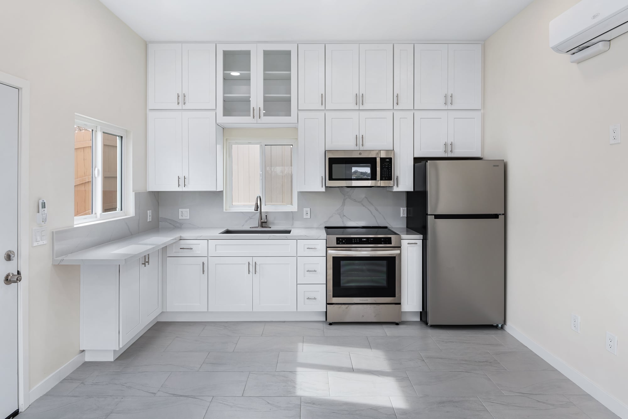 ADU kitchen with white shaker cabinetry, stainless appliances and a wall-mounted mini-split