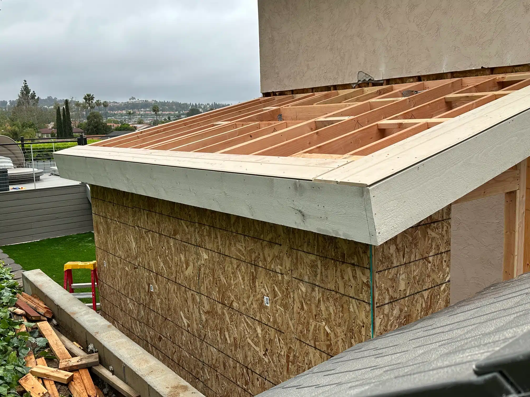 The addition roof sheathed, with the valley beyond