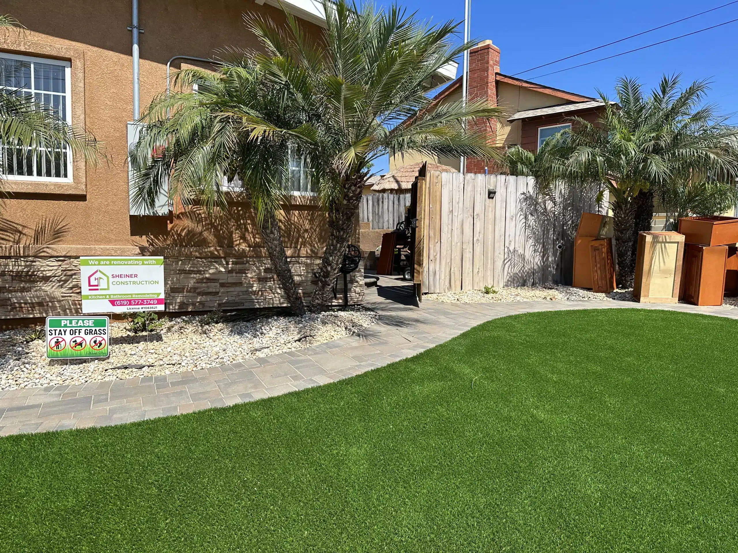 Rear yard of the San Diego property with artificial turf and mature palms