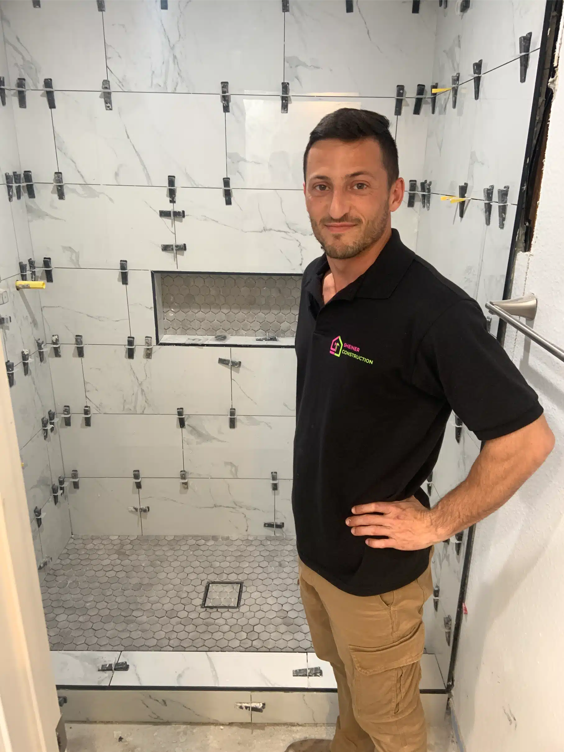 Joseph Sheiner in the shower enclosure while the wall tile is still being set