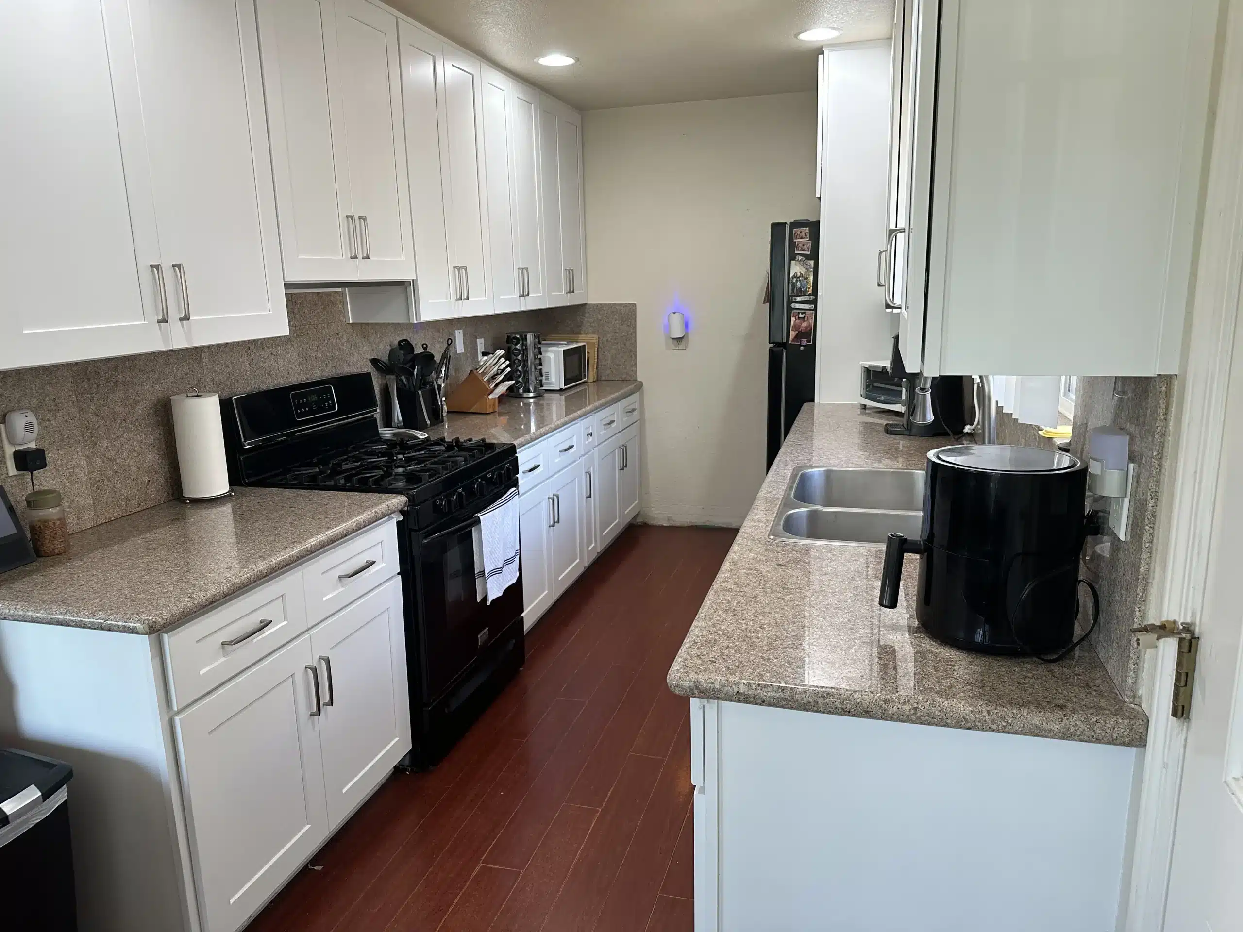 Completed San Diego galley kitchen with white shaker cabinetry and black appliances