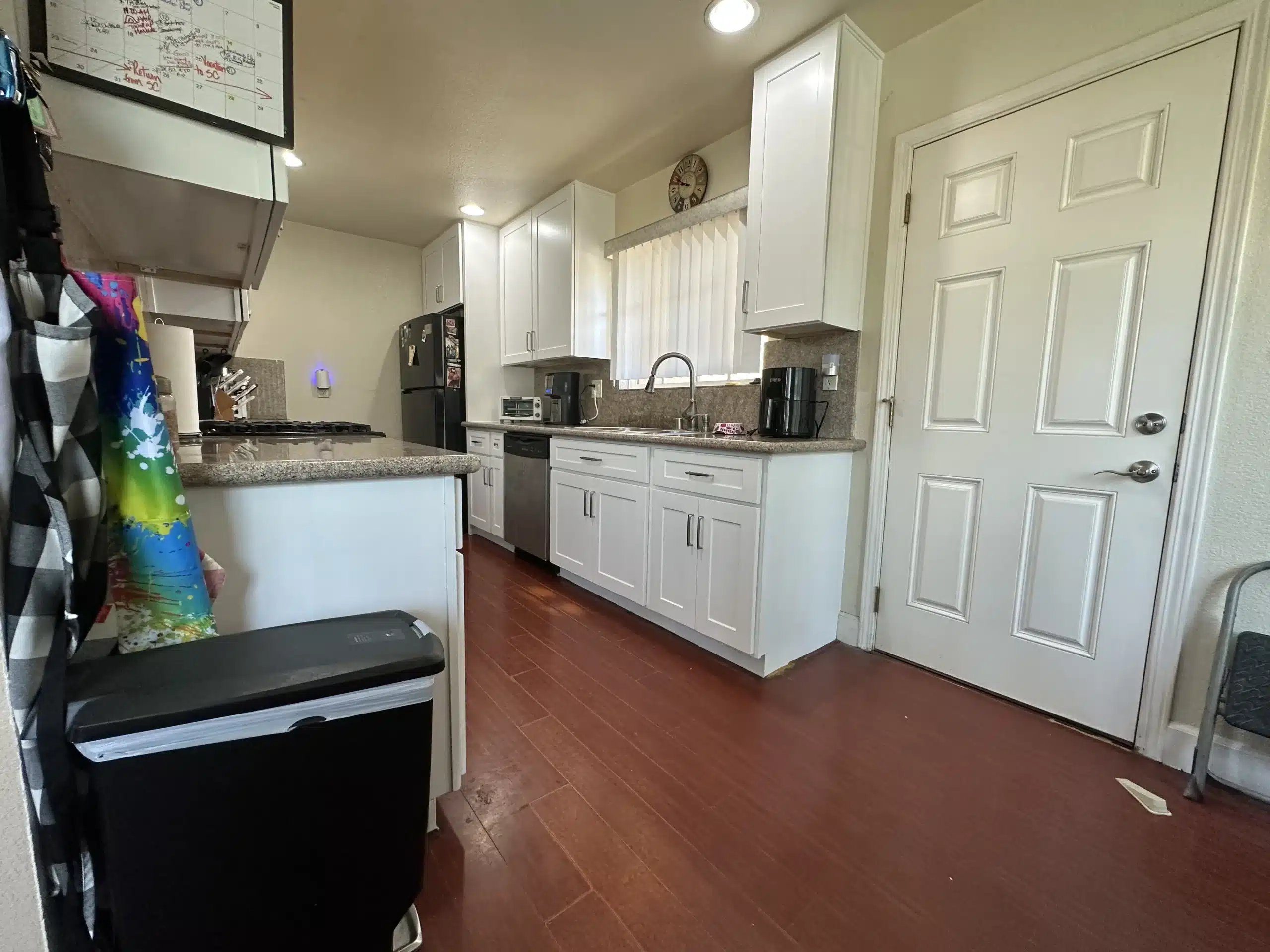 Finished galley kitchen looking toward the door, with white cabinetry along both runs