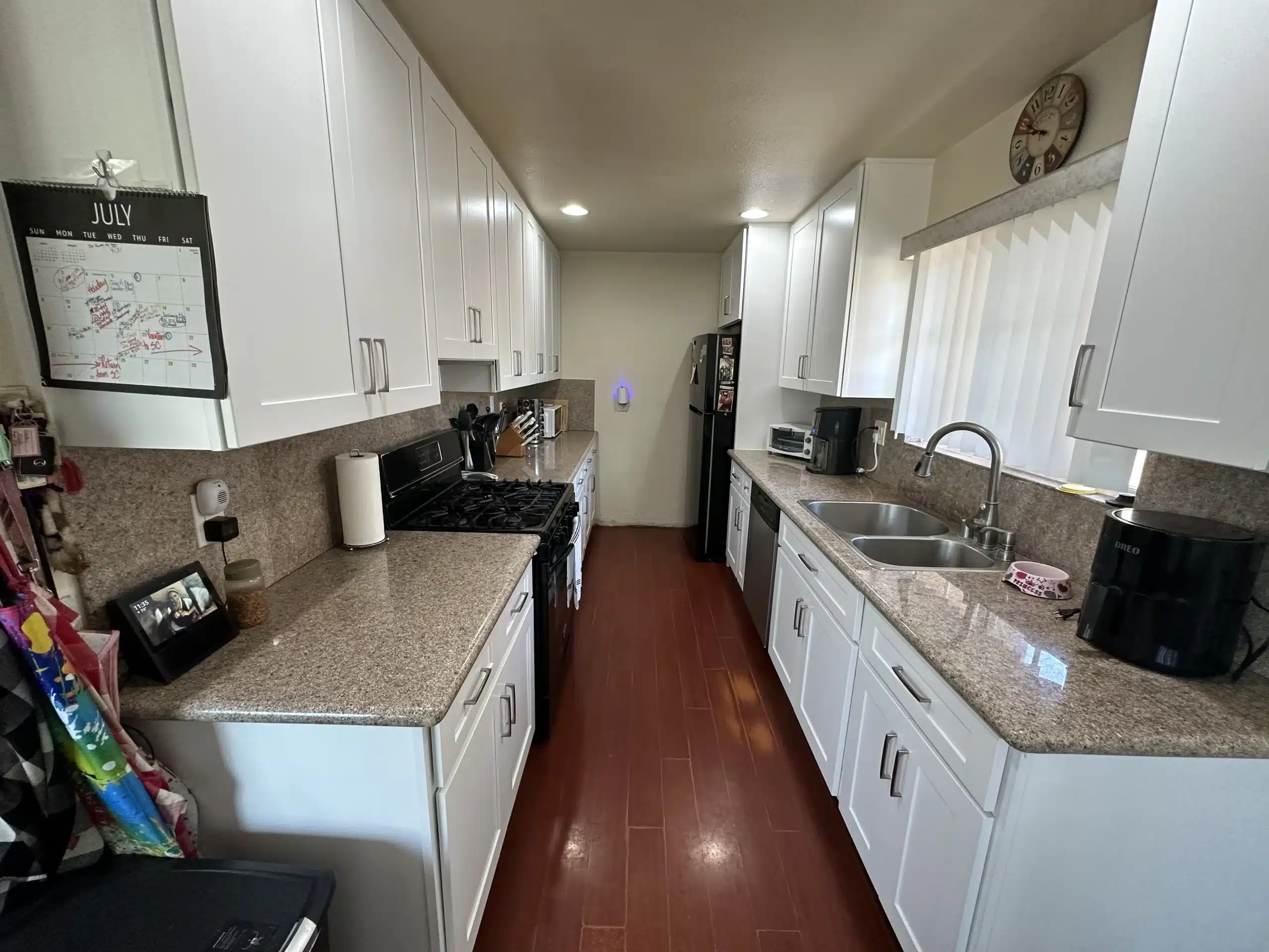 The same galley kitchen after the remodel, with white shaker cabinetry and stone-look counters