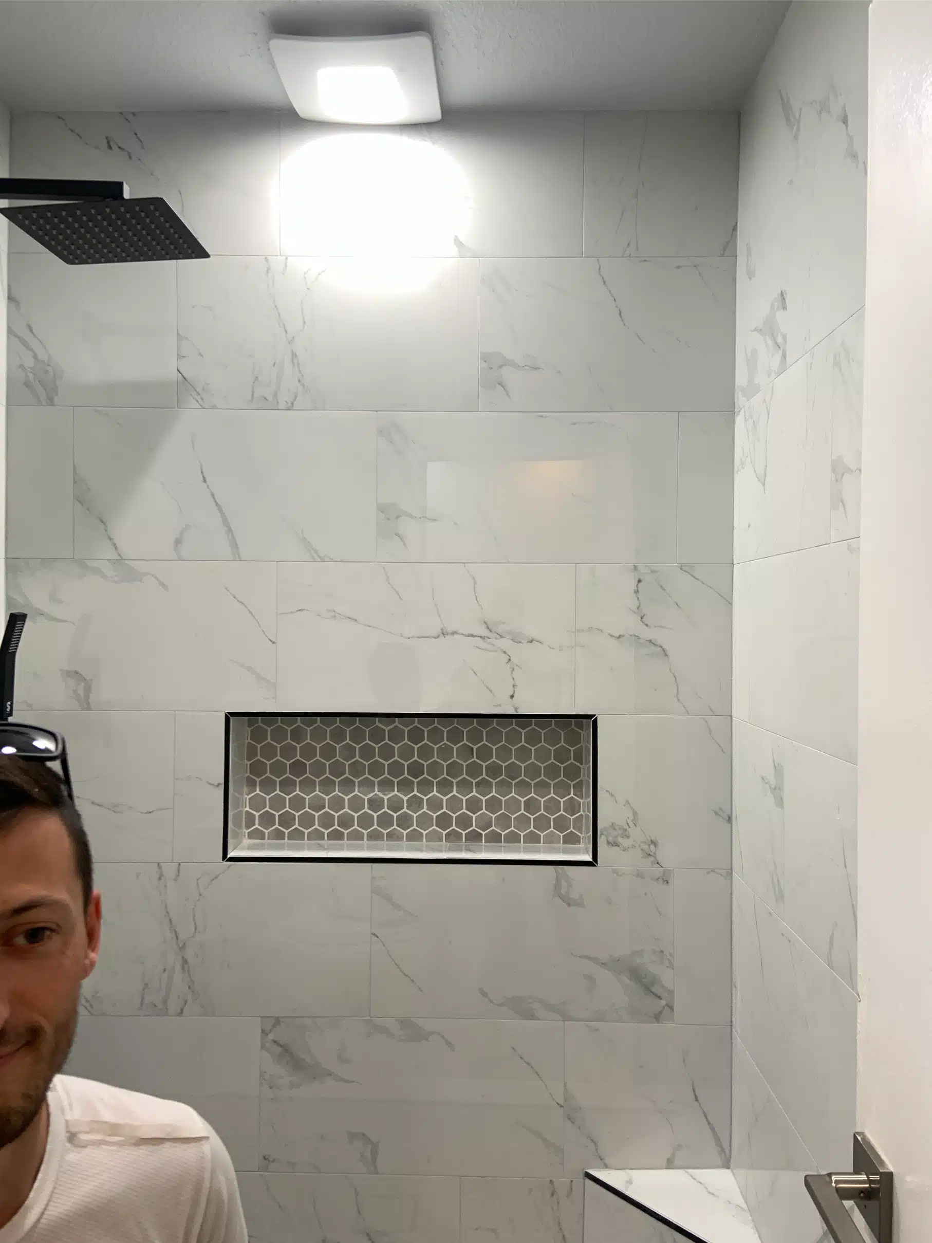 Matte black rain head mounted above the recessed mosaic niche