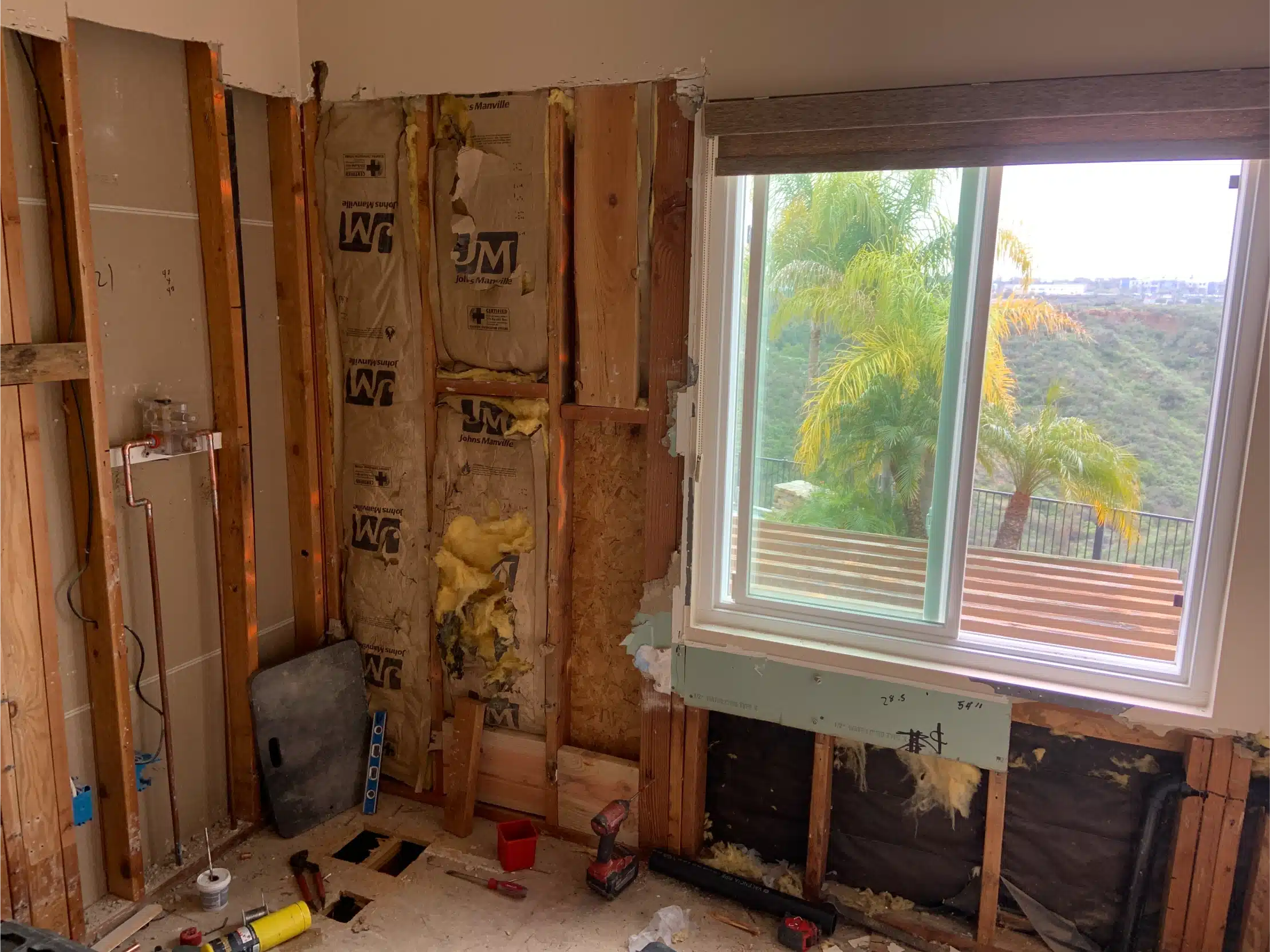 The bathroom open to the studs, with the window opening and services visible