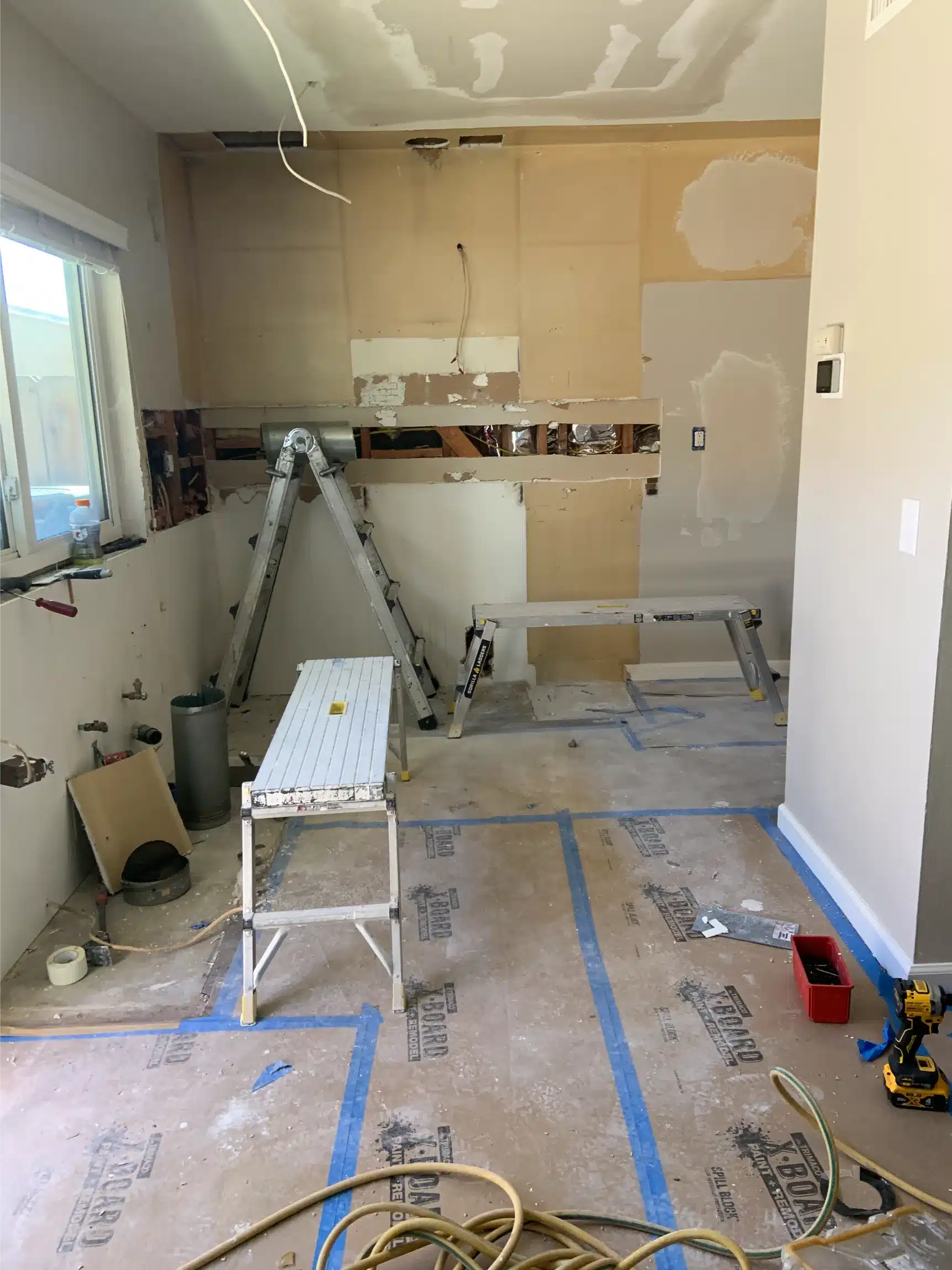 The kitchen stripped of cabinets and appliances with bare walls and exposed subfloor