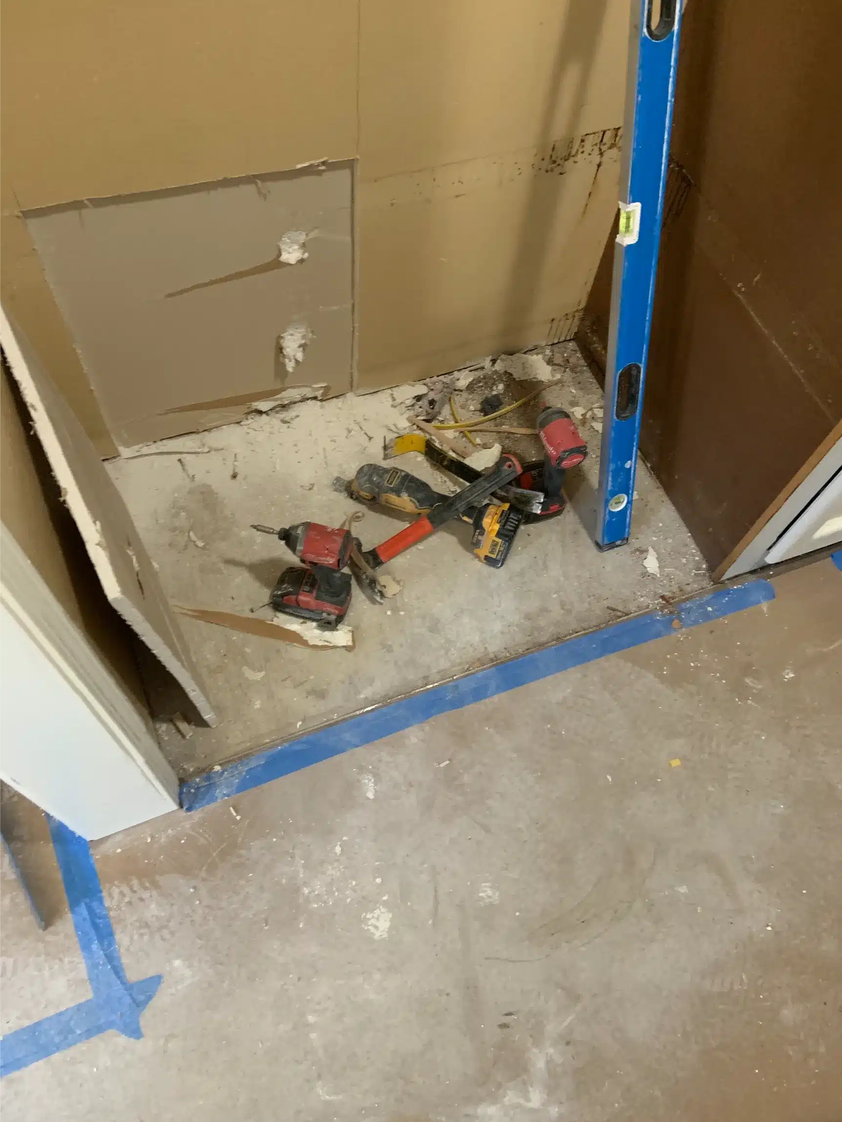 Wall repair underway with masked baseboards and a drywall panel set against the corner