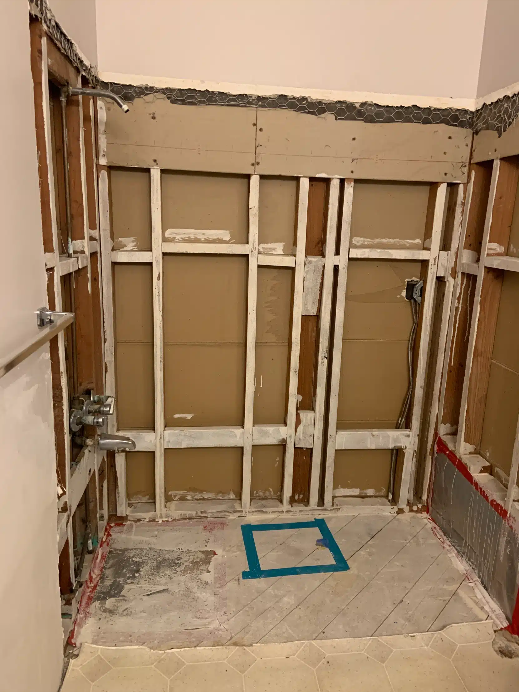 The bathroom stripped to bare studs with the shower area opened up