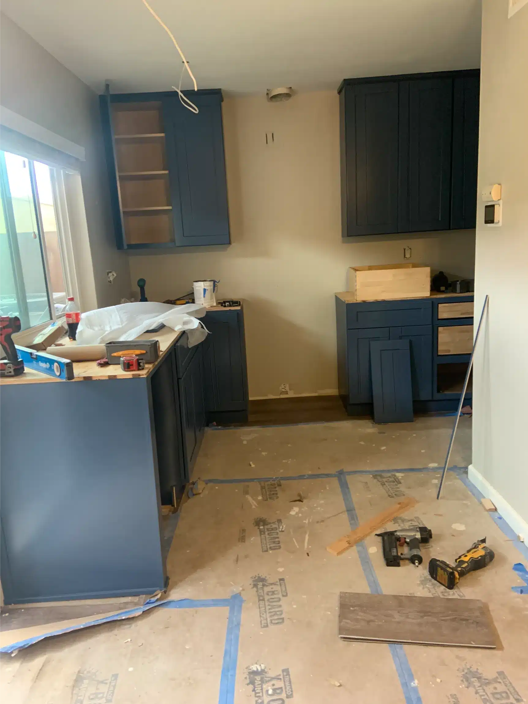 Navy shaker cabinet boxes installed along the wall with floors covered for protection