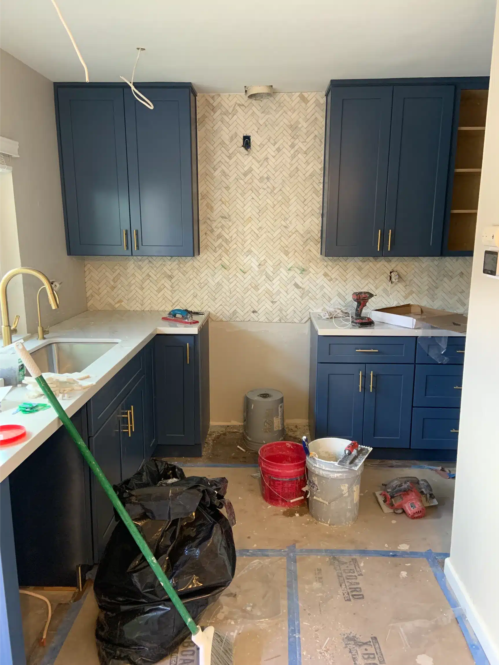 The kitchen with cabinets and sink installed and the wall above the counter bare before tiling