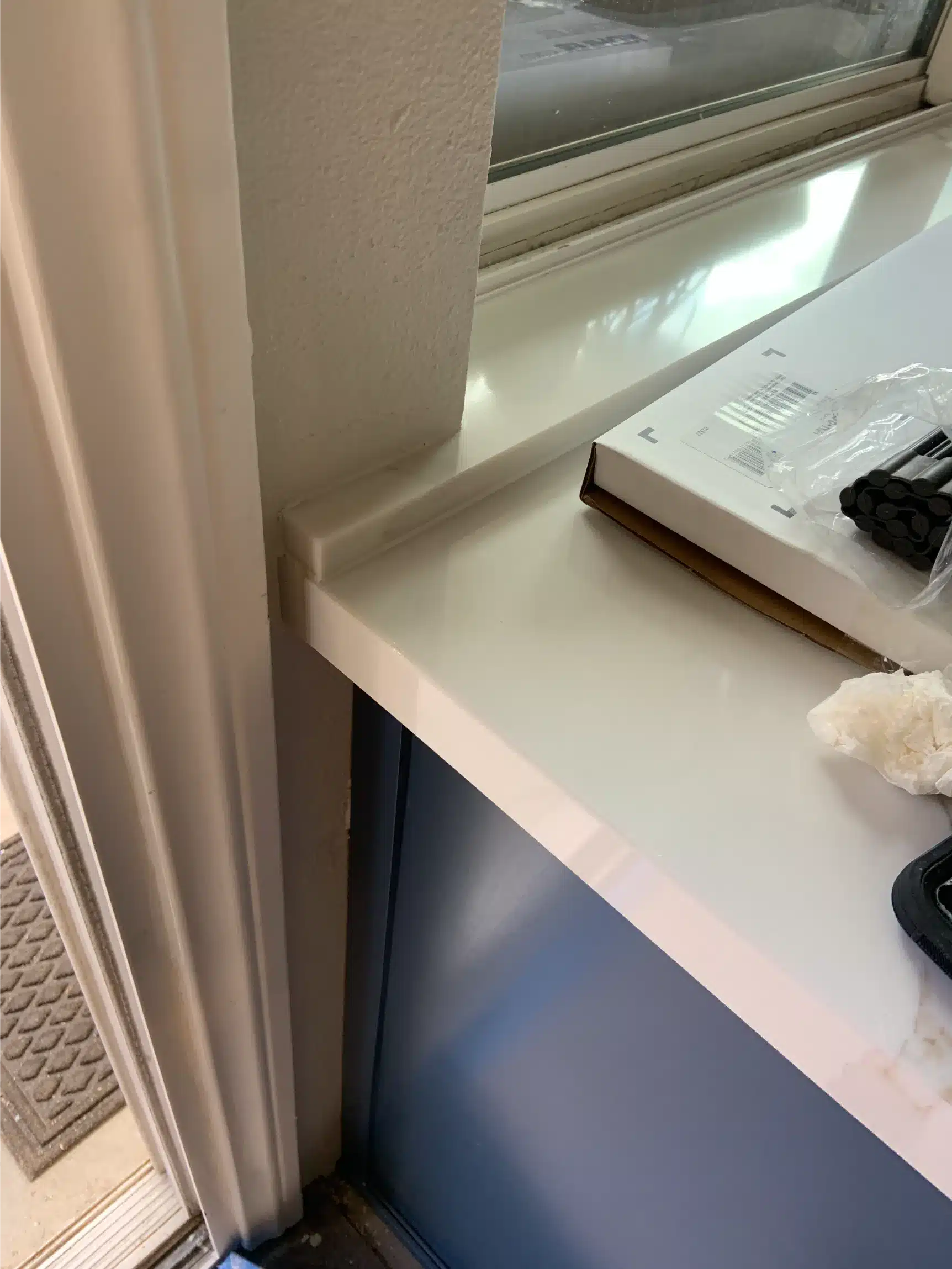 Detail of the stone counter edge meeting a navy cabinet beneath the window