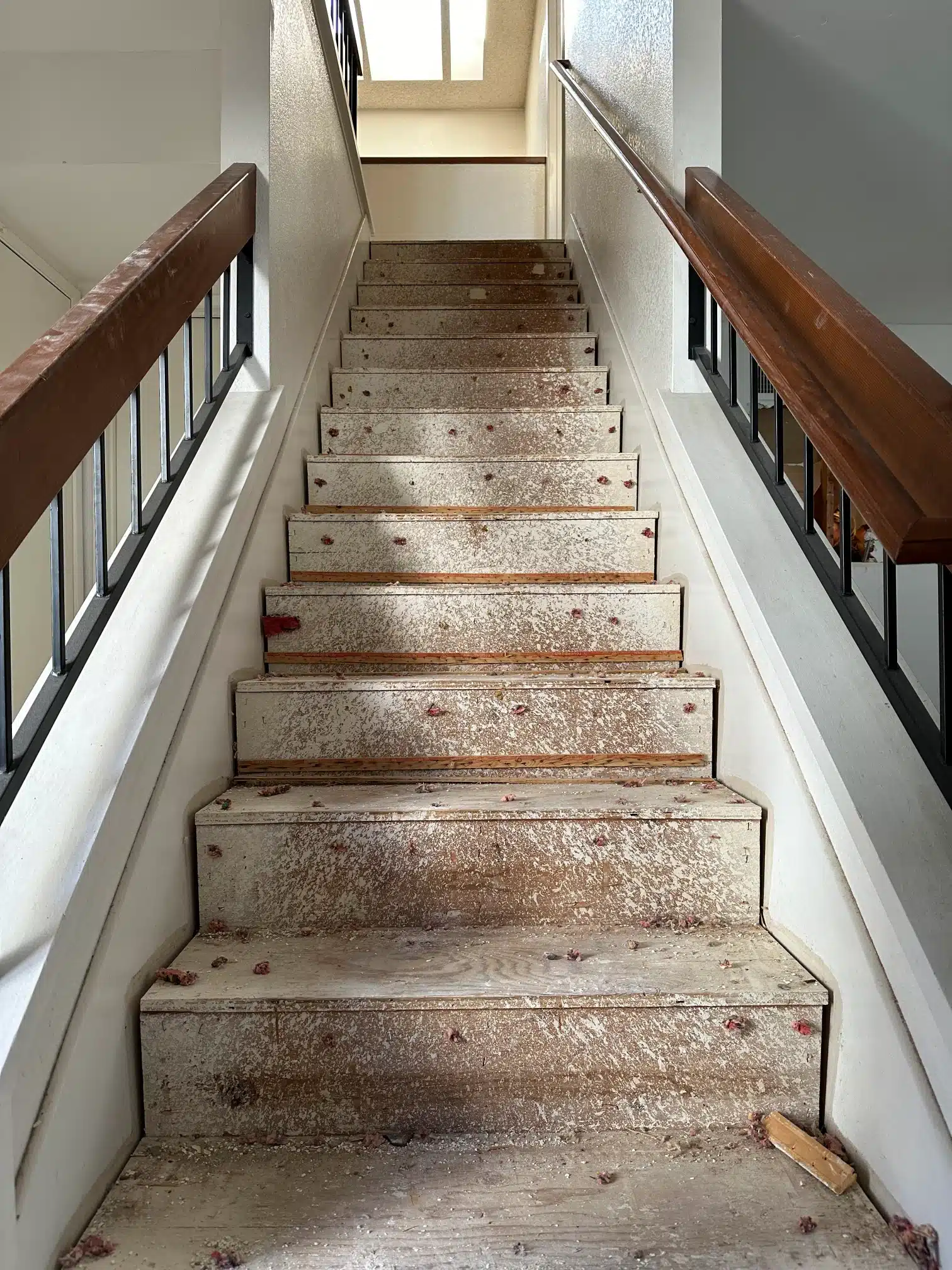 The original staircase with worn treads and a dated railing before the remodel