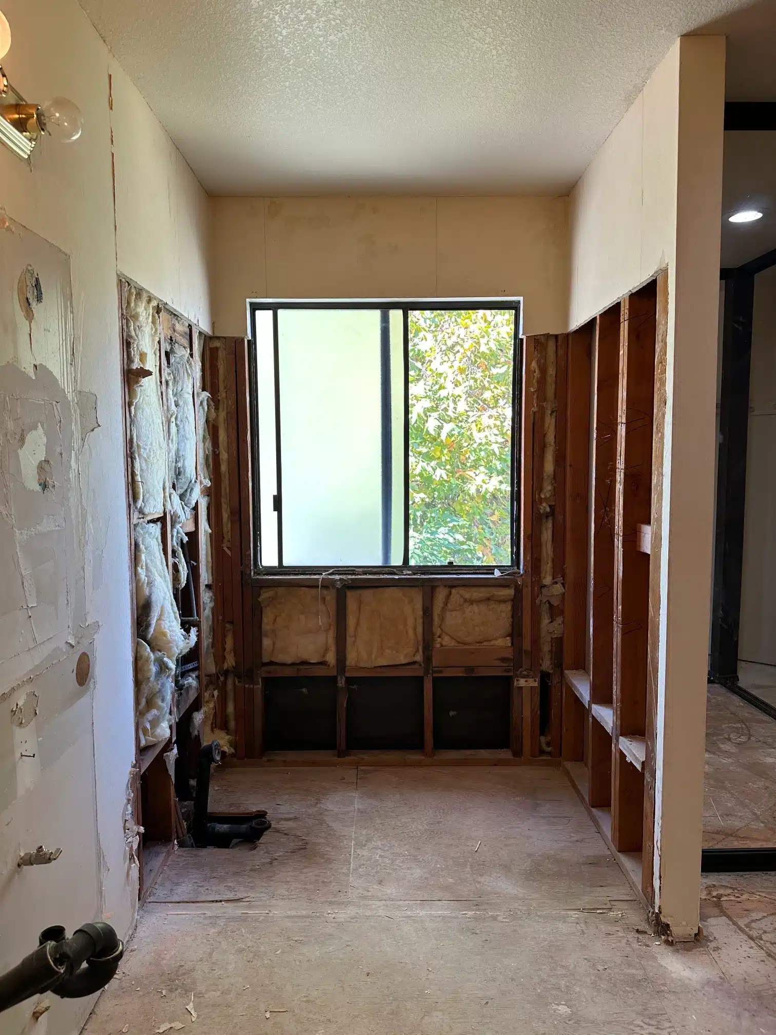 The bathroom stripped to the framing with the window opening exposed